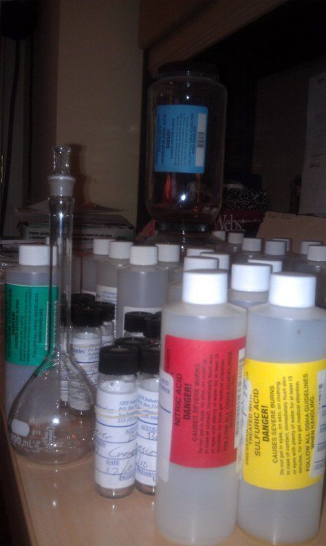 A bunch of bottles on a table one of which has a yellow label