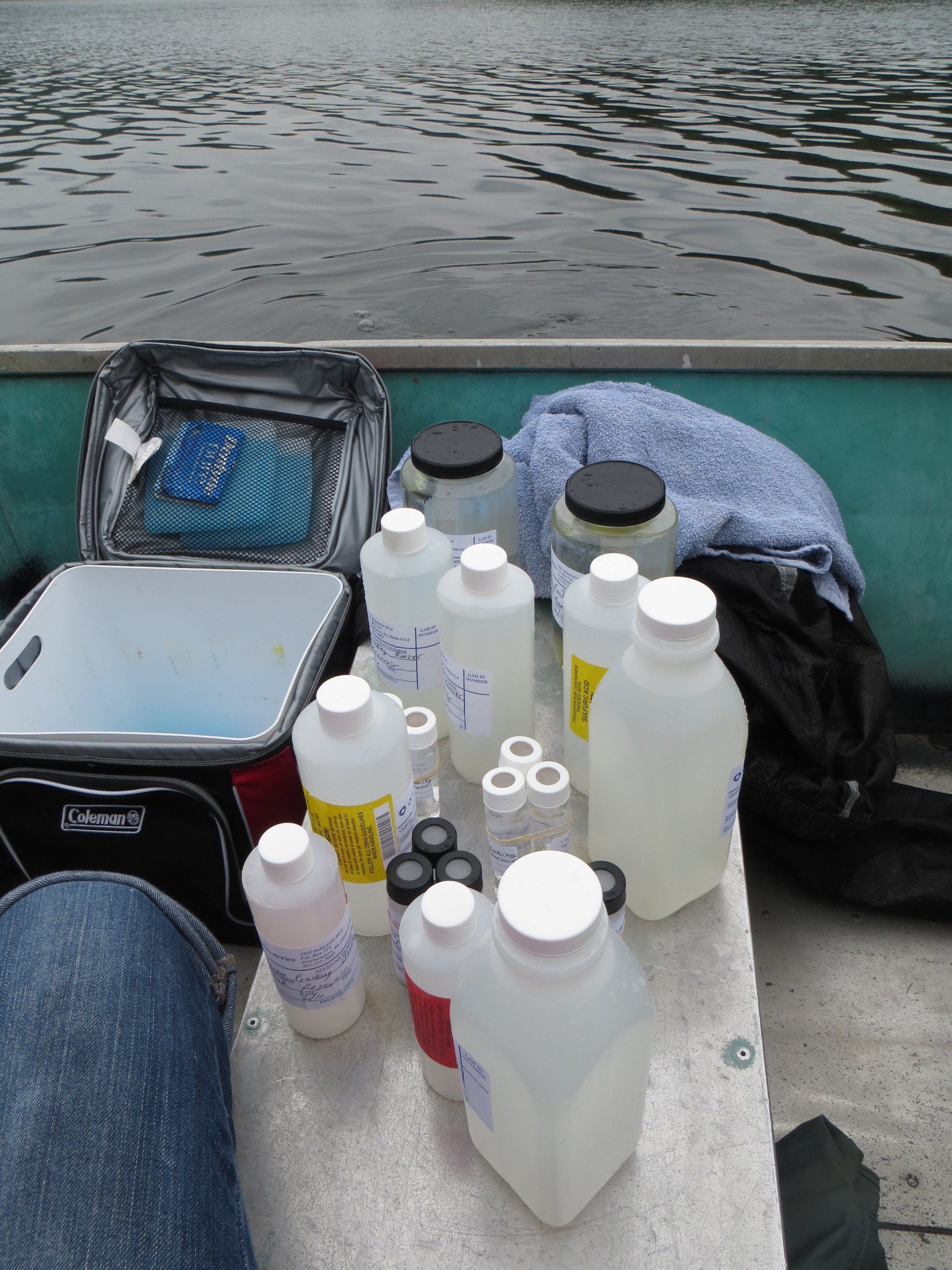 Several bottles are sitting on a table in front of a boat