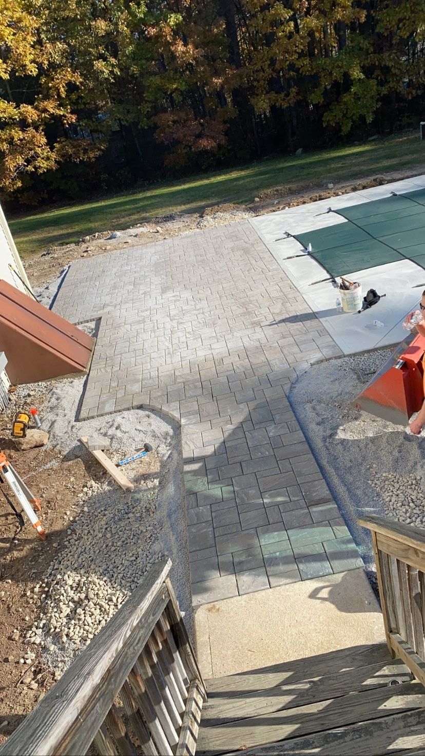 Concrete patio and steps under construction near a swimming pool. Sunlight on fall foliage.