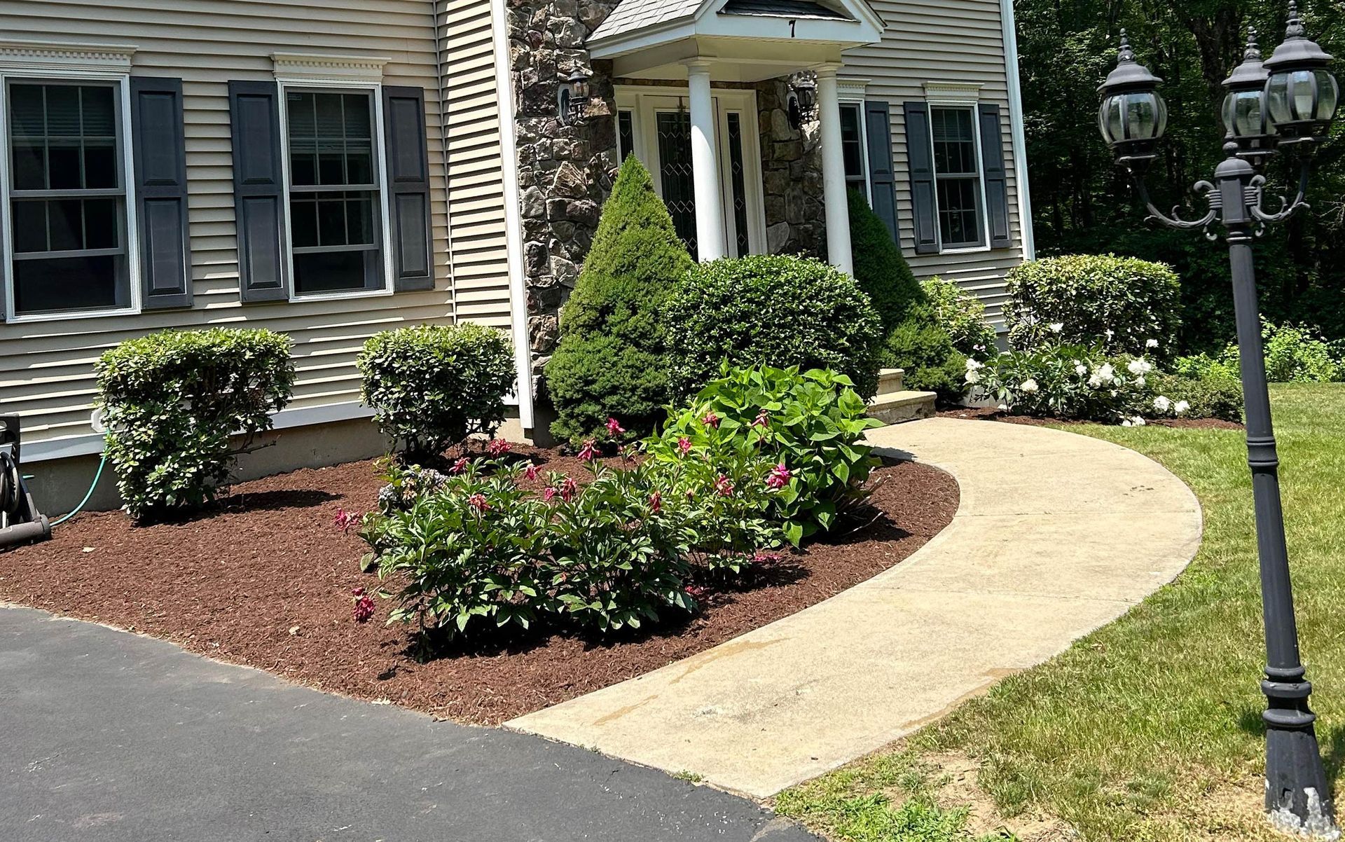 Two-story house with tan siding, backyard with green lawn, patio furniture, and landscaping.