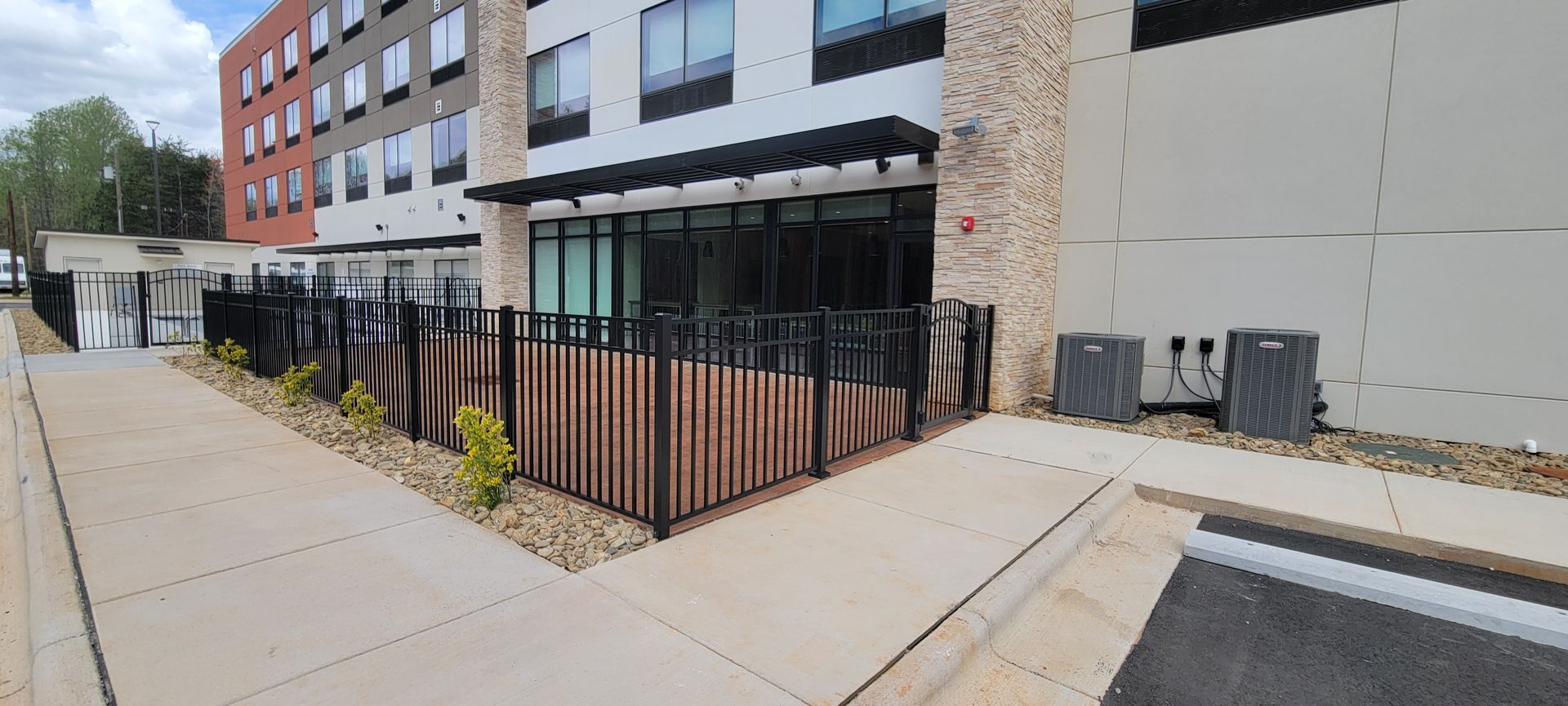 A building with a fence around it and a sidewalk in front of it.