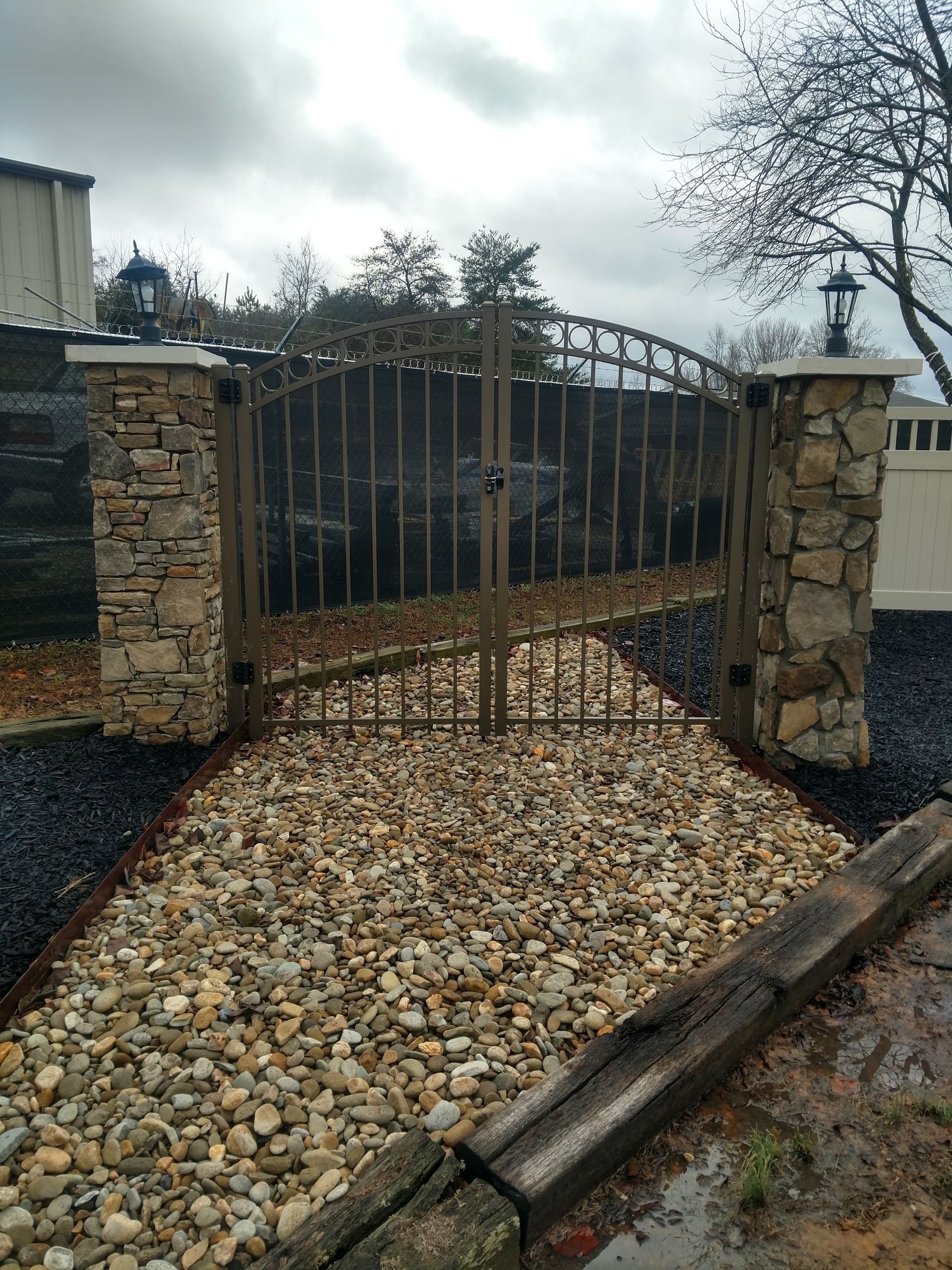 A metal gate is surrounded by rocks and a stone wall.