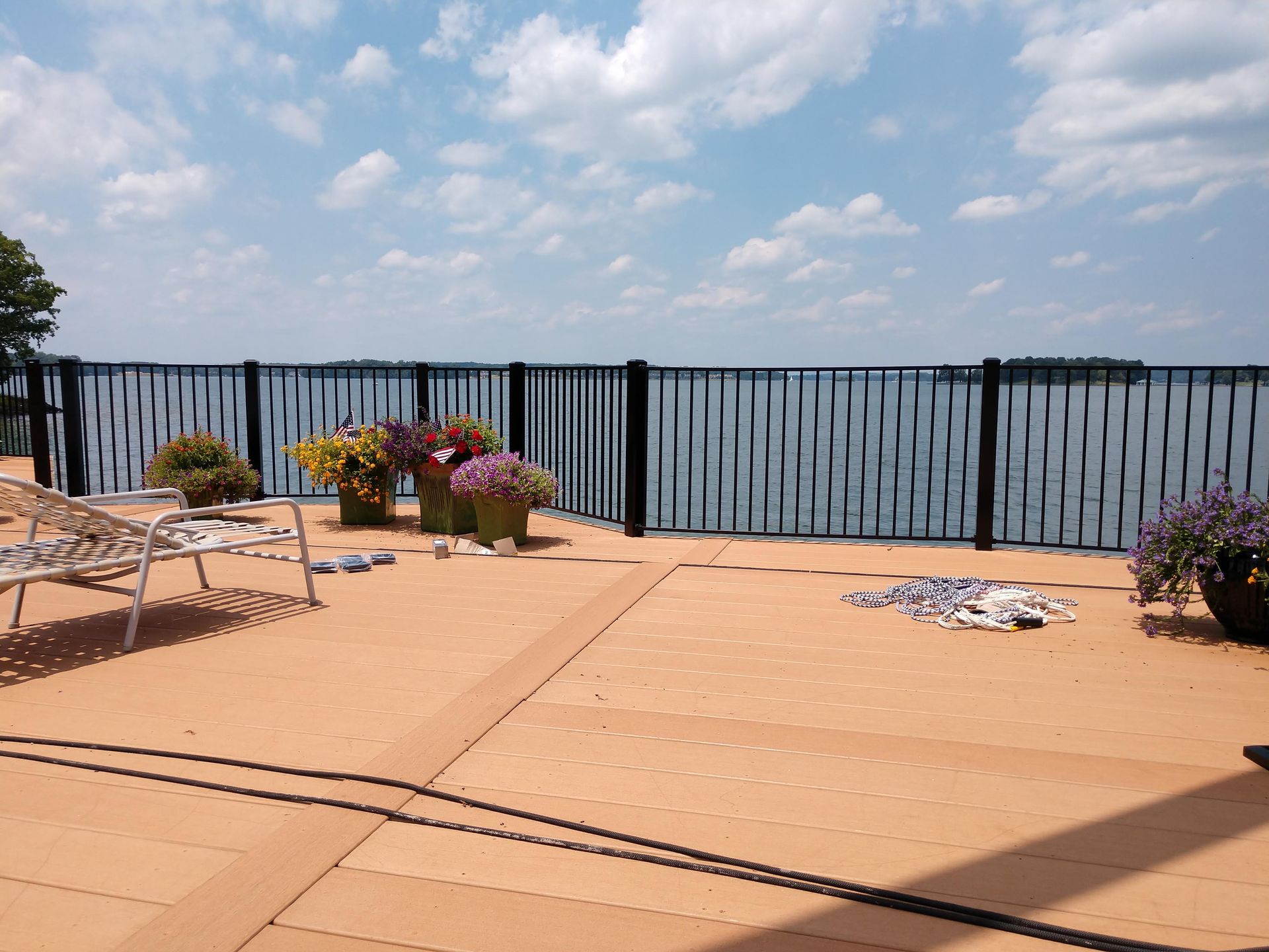 A patio with flowers and chairs overlooking a body of water