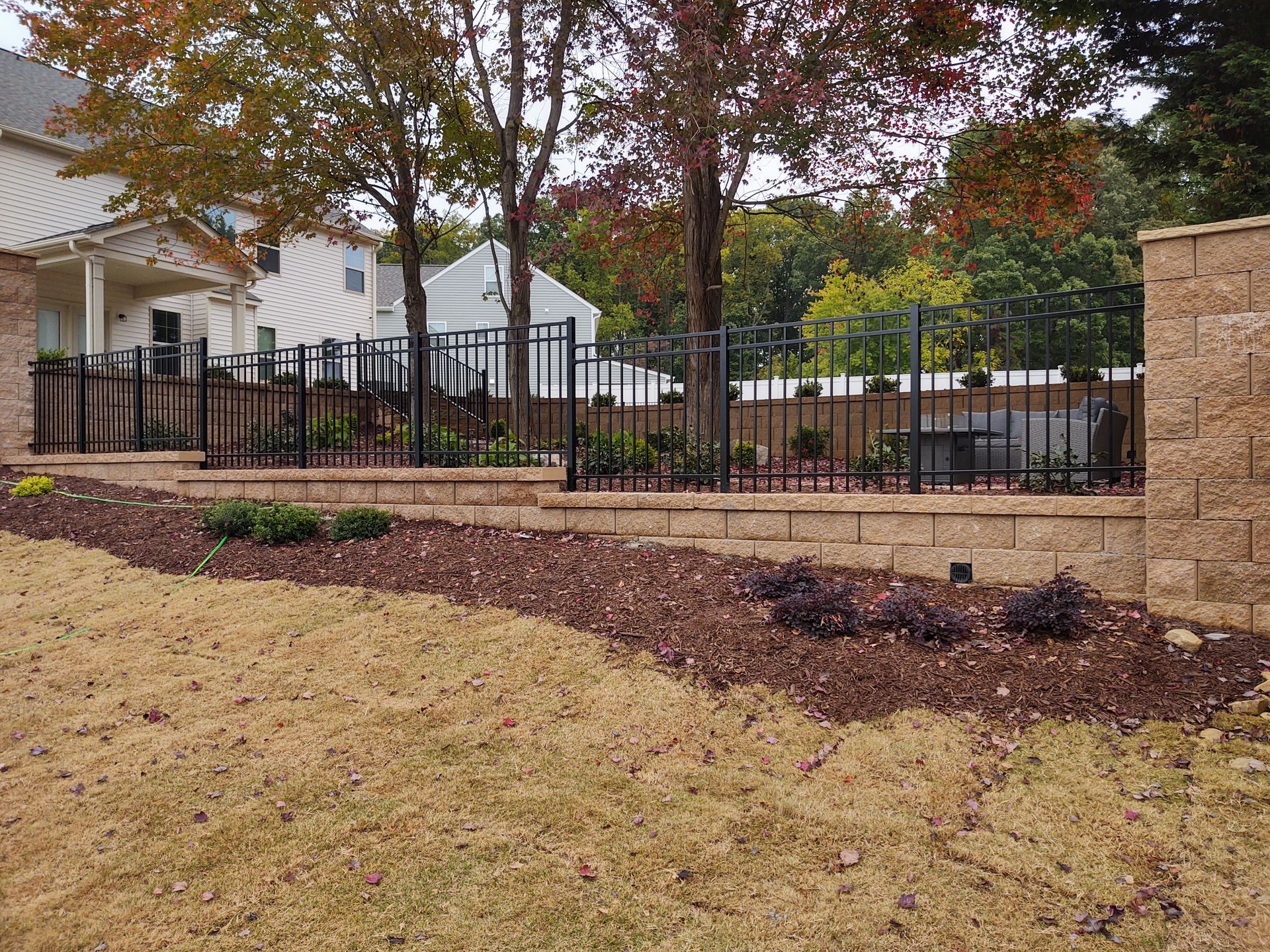 A brick wall with a metal fence in front of a house.