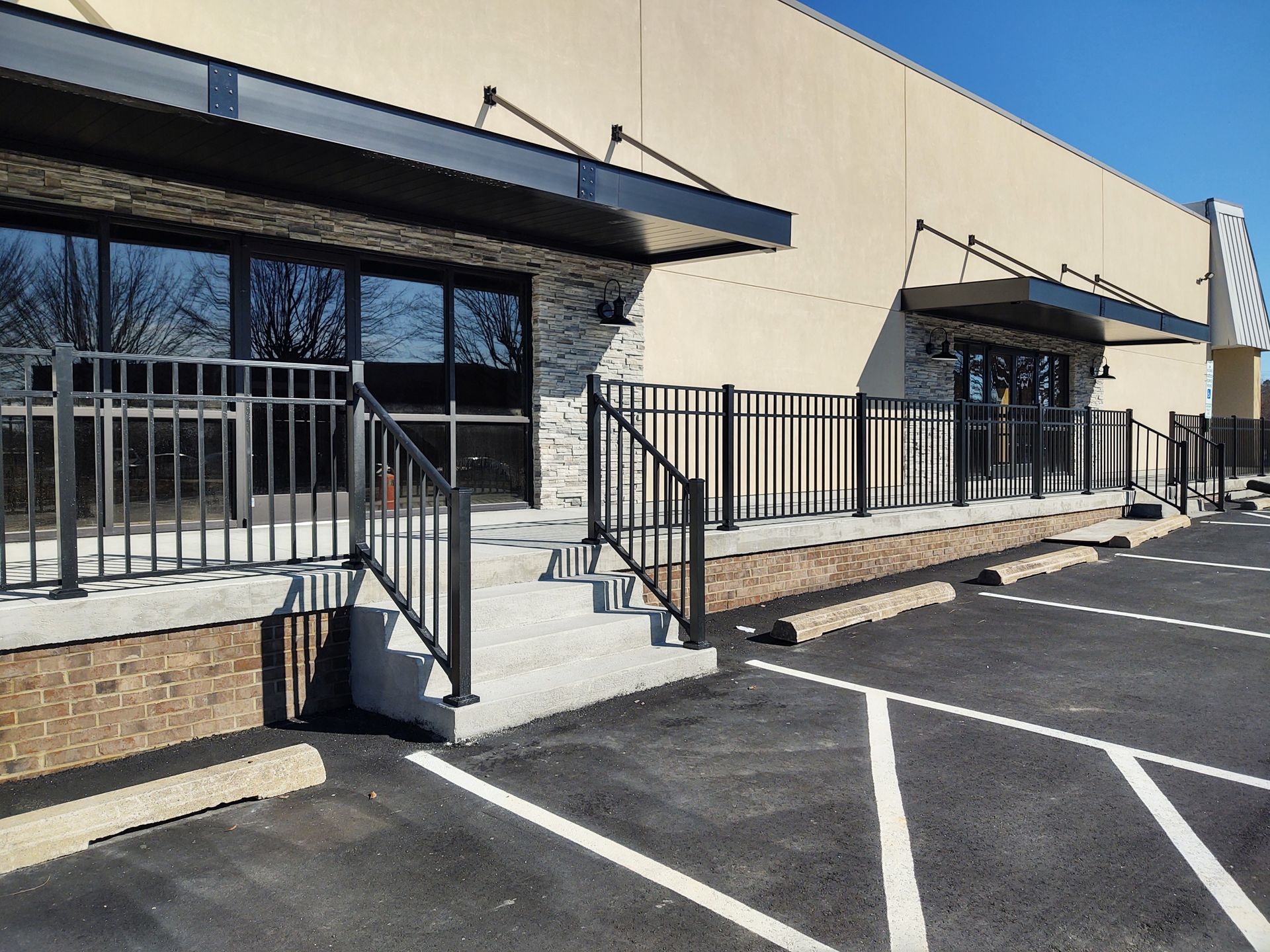 A building with stairs leading up to it and a parking lot in front of it.