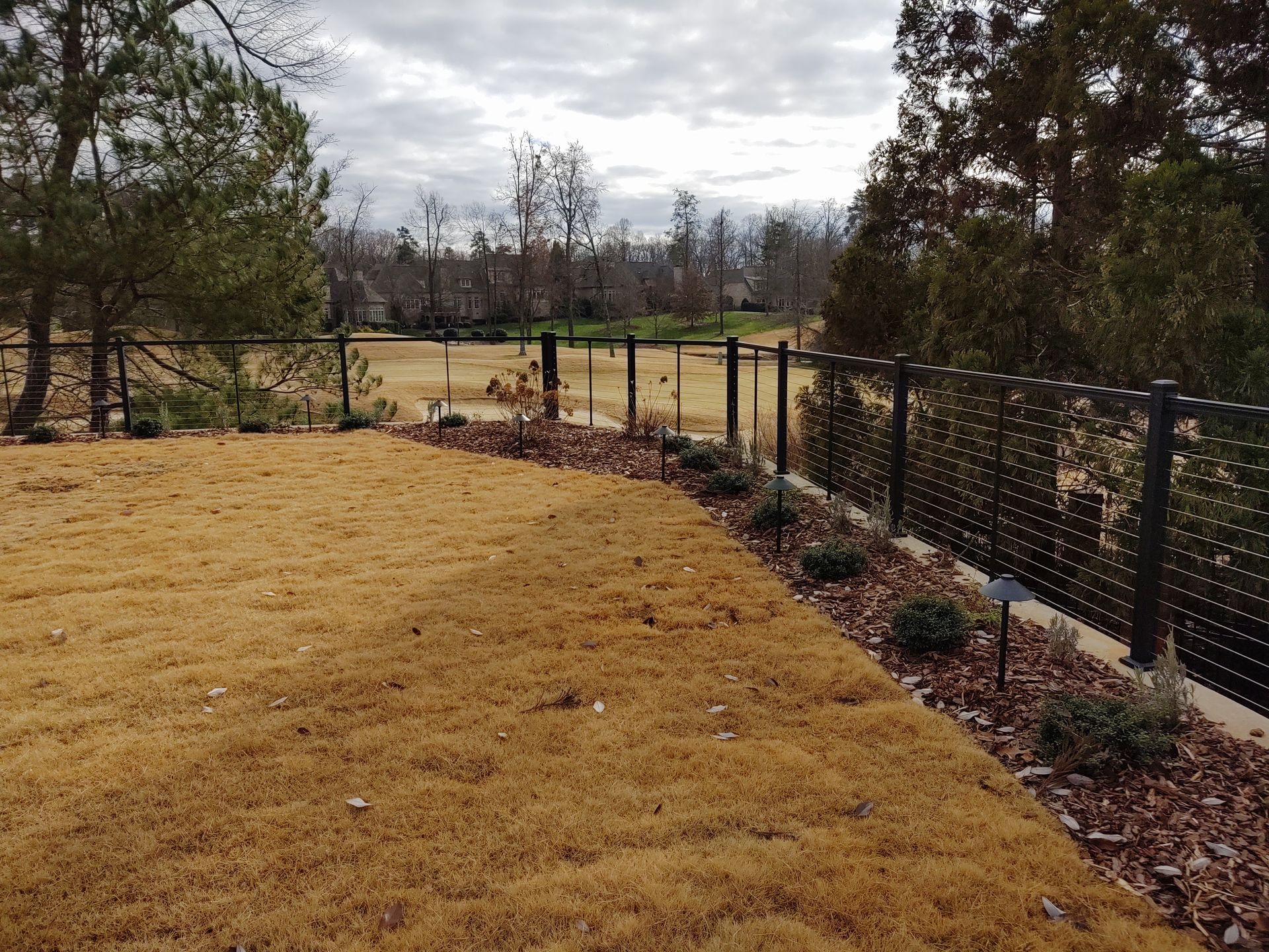 A fence surrounds a lush green field with trees in the background
