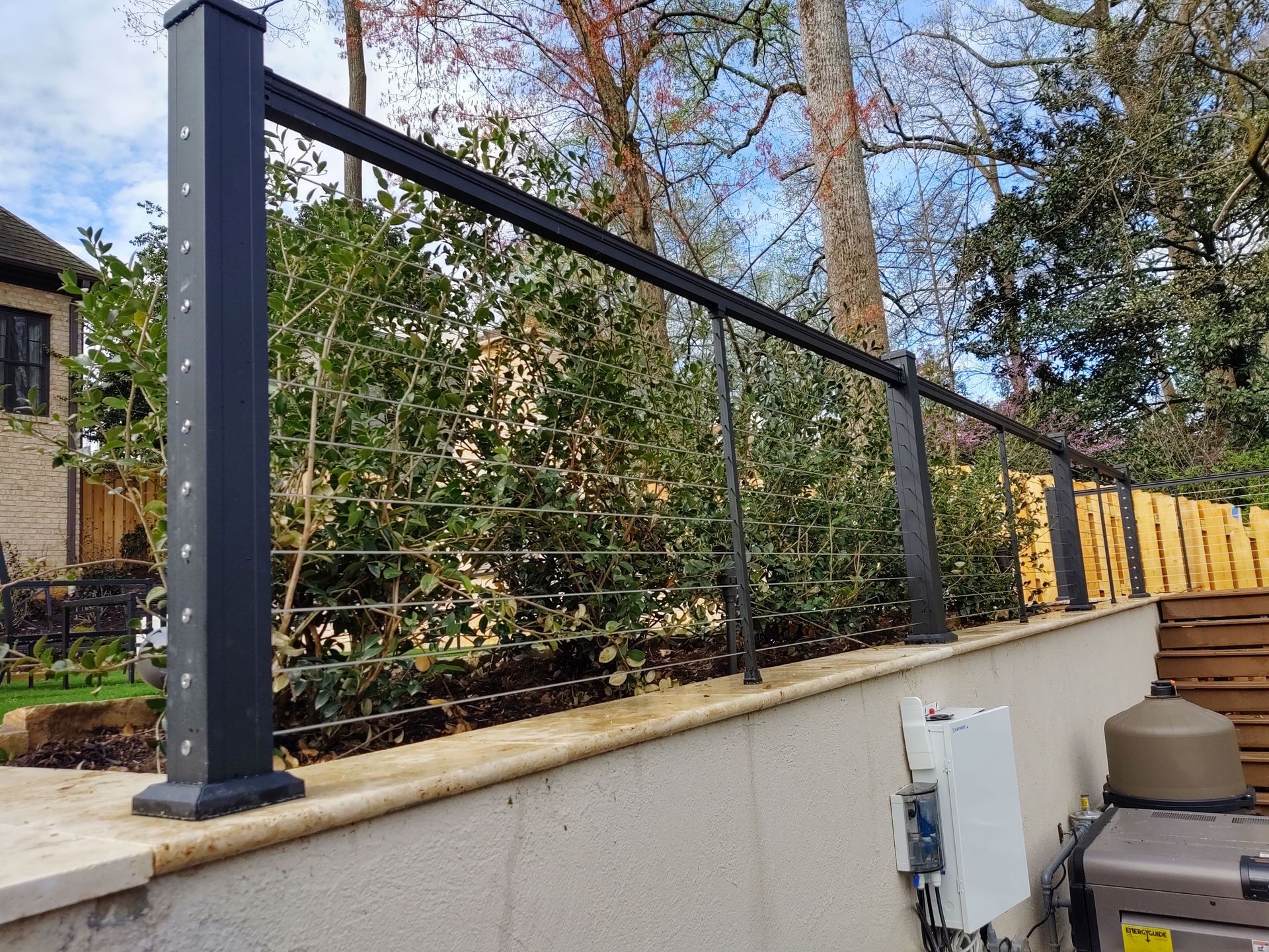 A black fence with a wooden fence in the background.