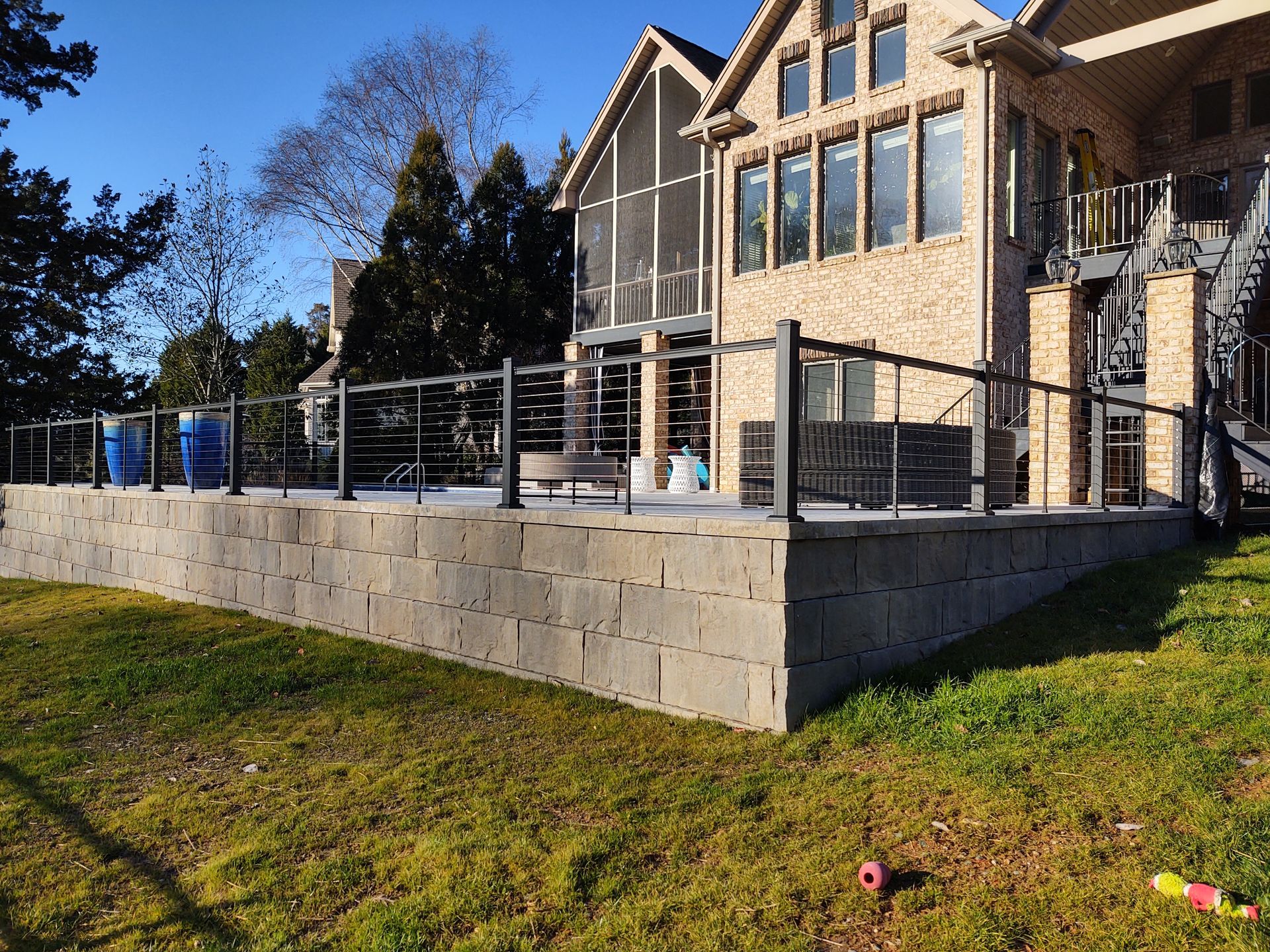 A large house with a brick wall and a stainless steel railing