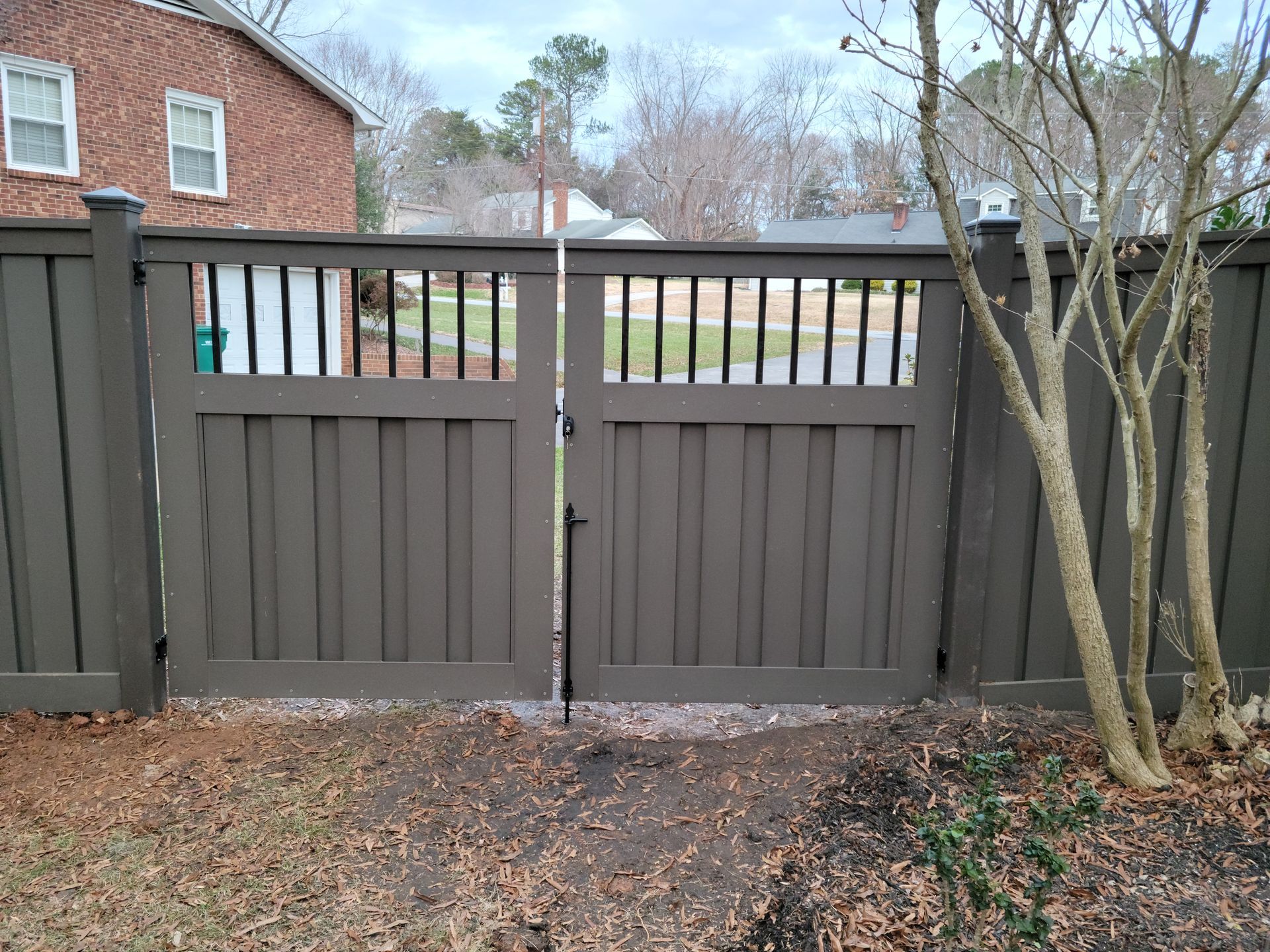 a wooden fence with a gate and a tree in front of it