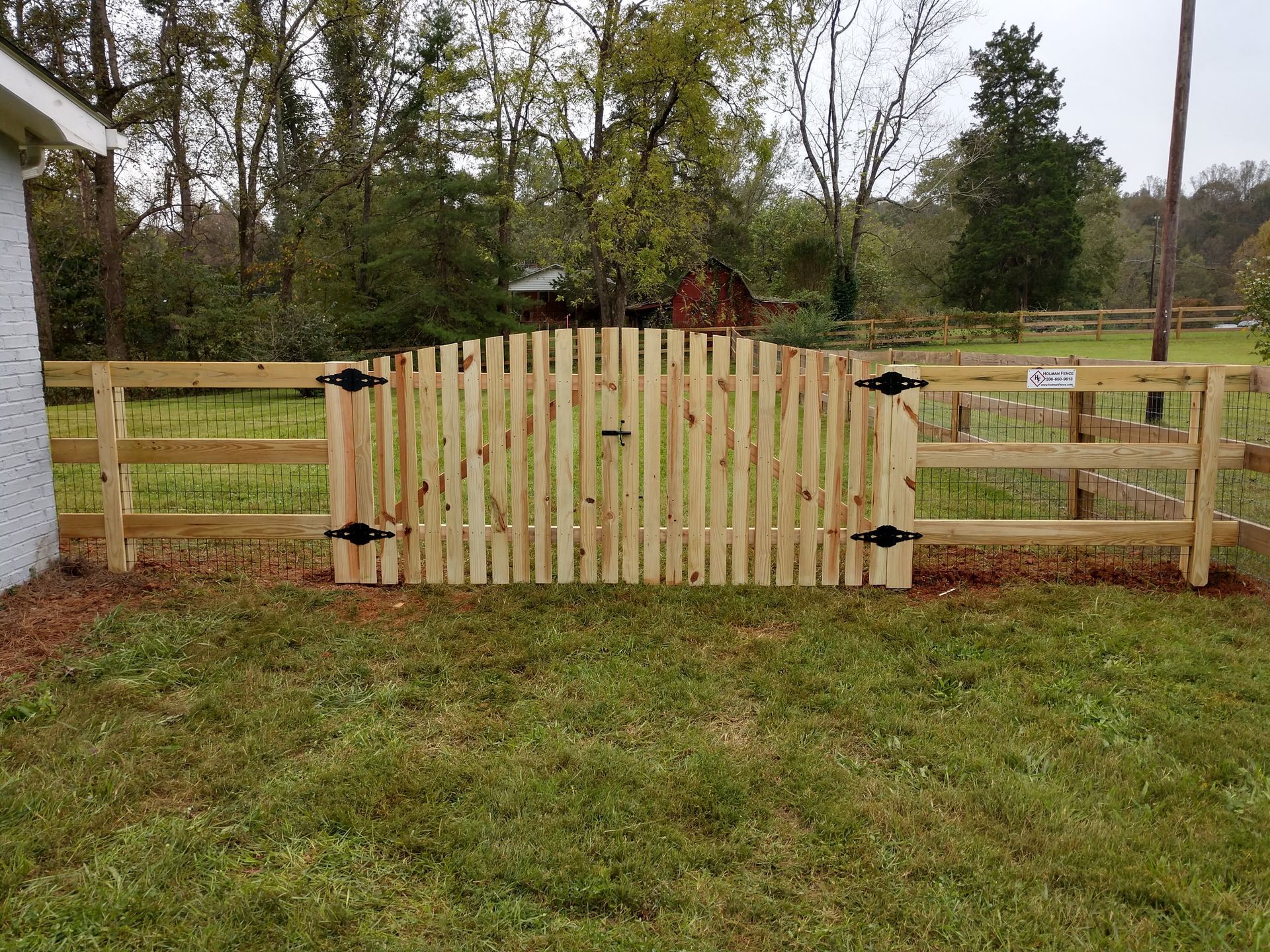 a wooden fence with a gate in the middle of a grassy field