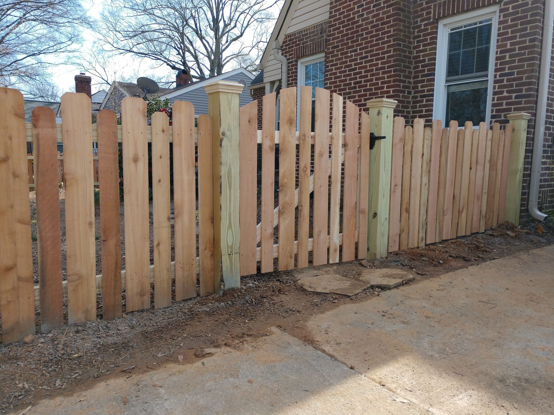 a wooden picket fence in front of a brick house