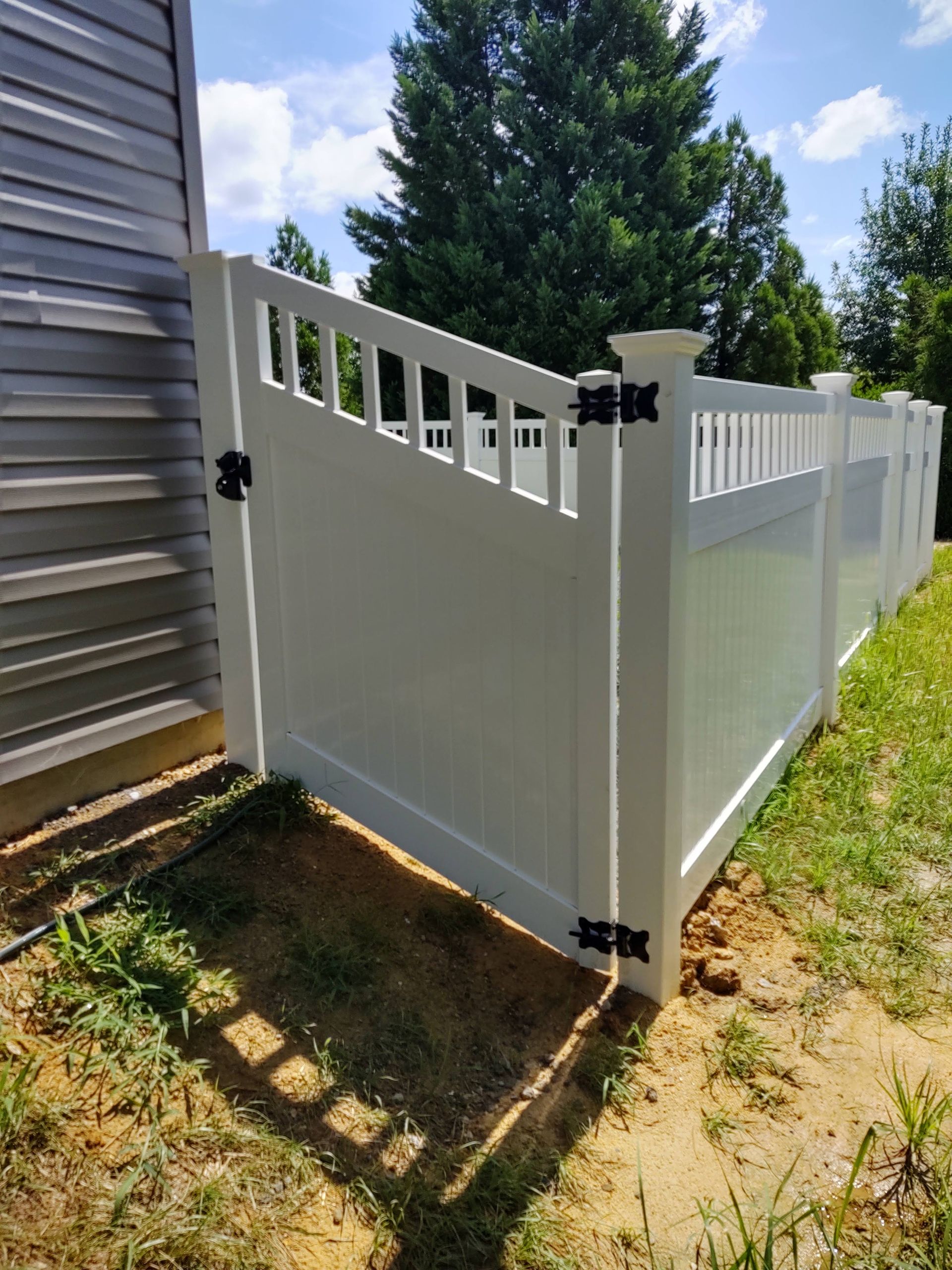 a white fence is sitting in the dirt next to a house