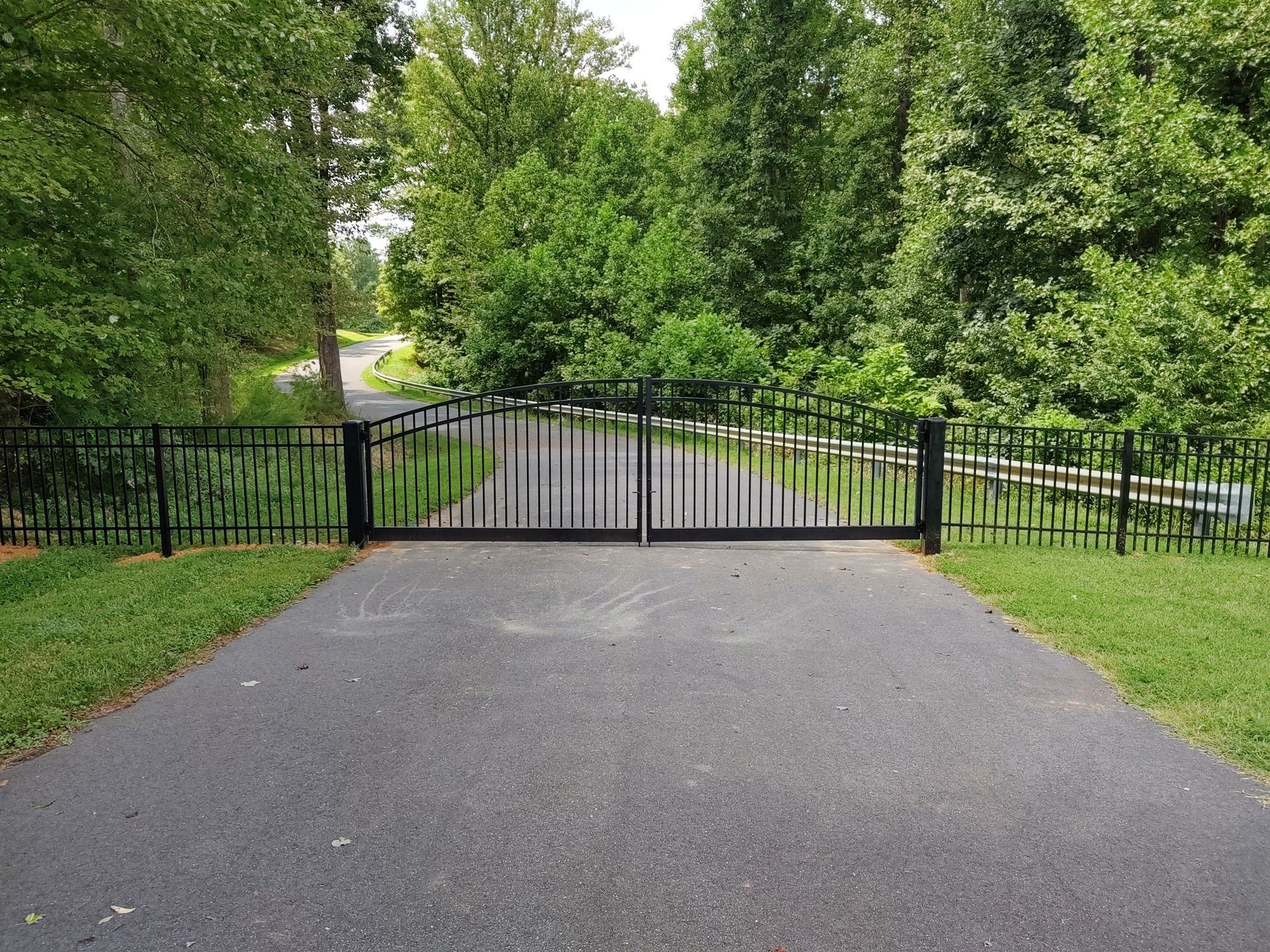 a fence along the side of a road with trees in the background
