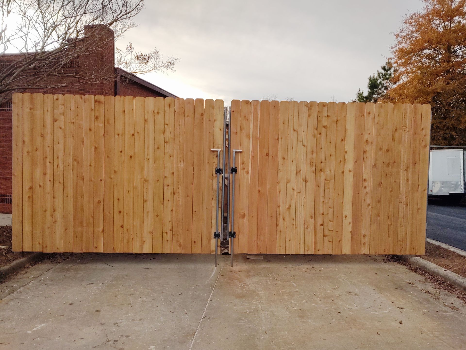 a wooden fence with a metal gate in front of a house