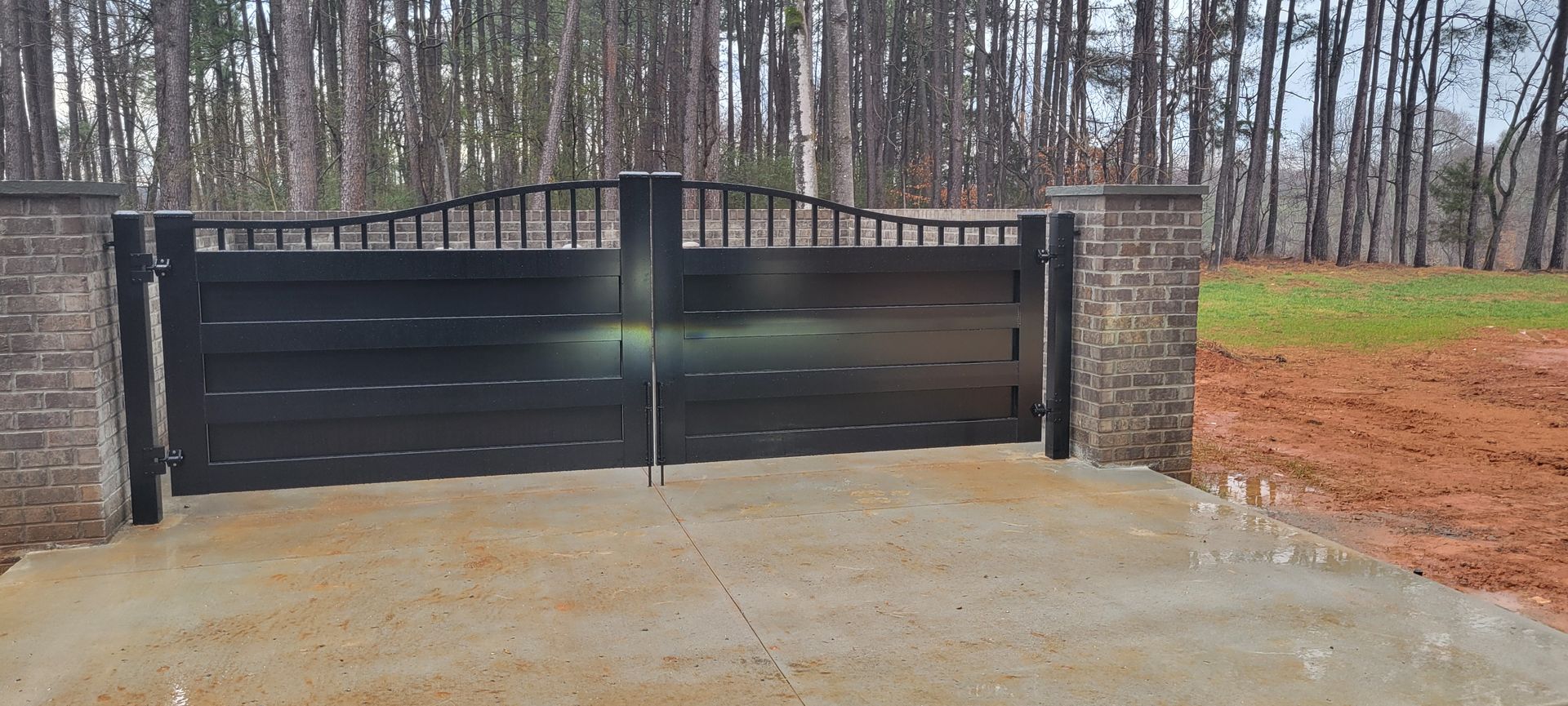 A black gate next to a brick wall