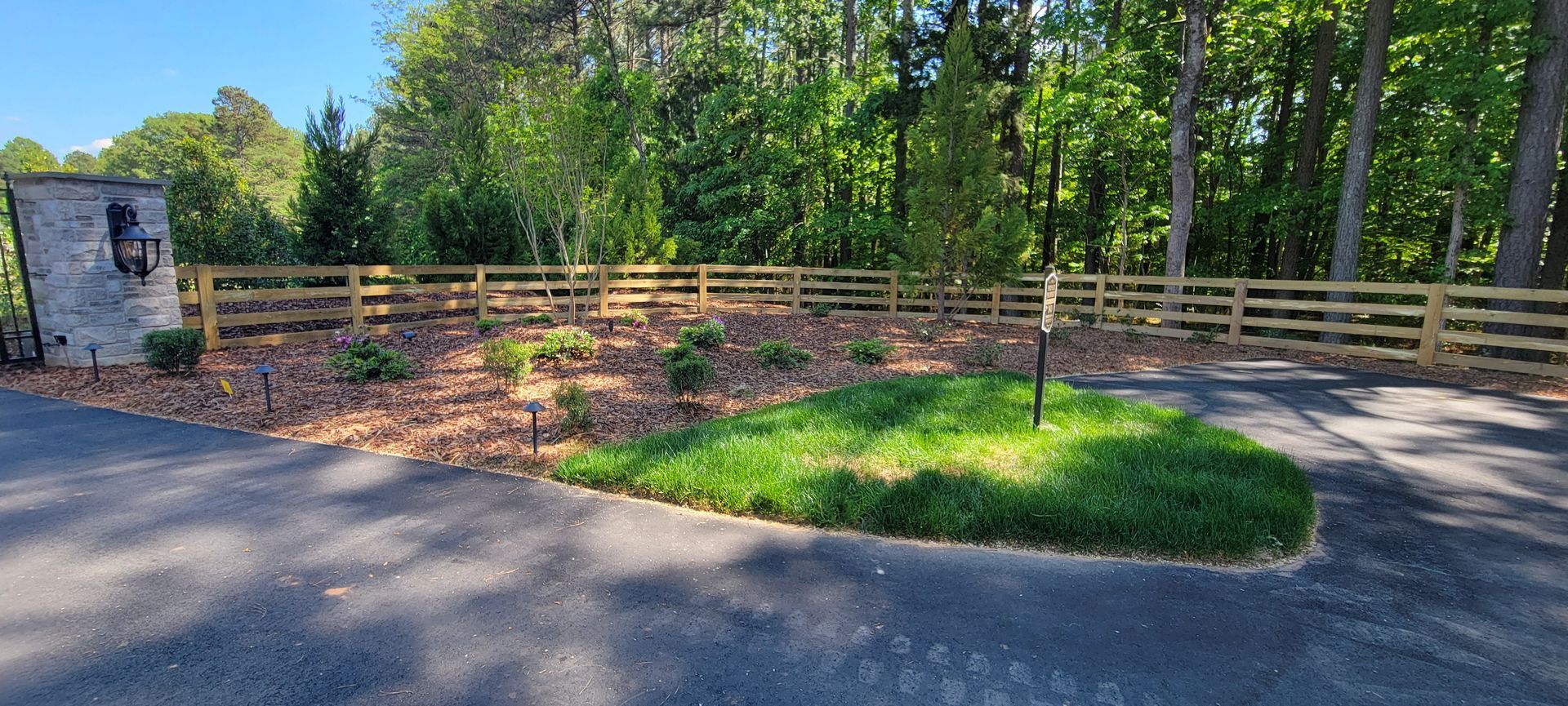 A wooden fence surrounds a grassy area next to a road