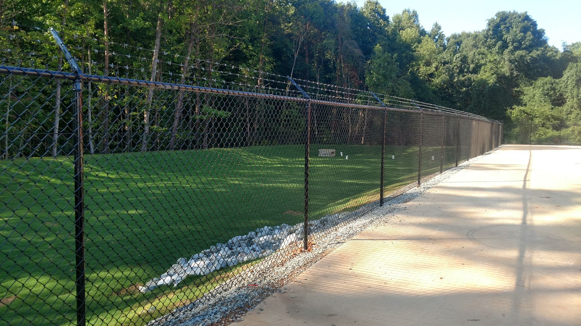 a chain link fence along the side of a dirt road
