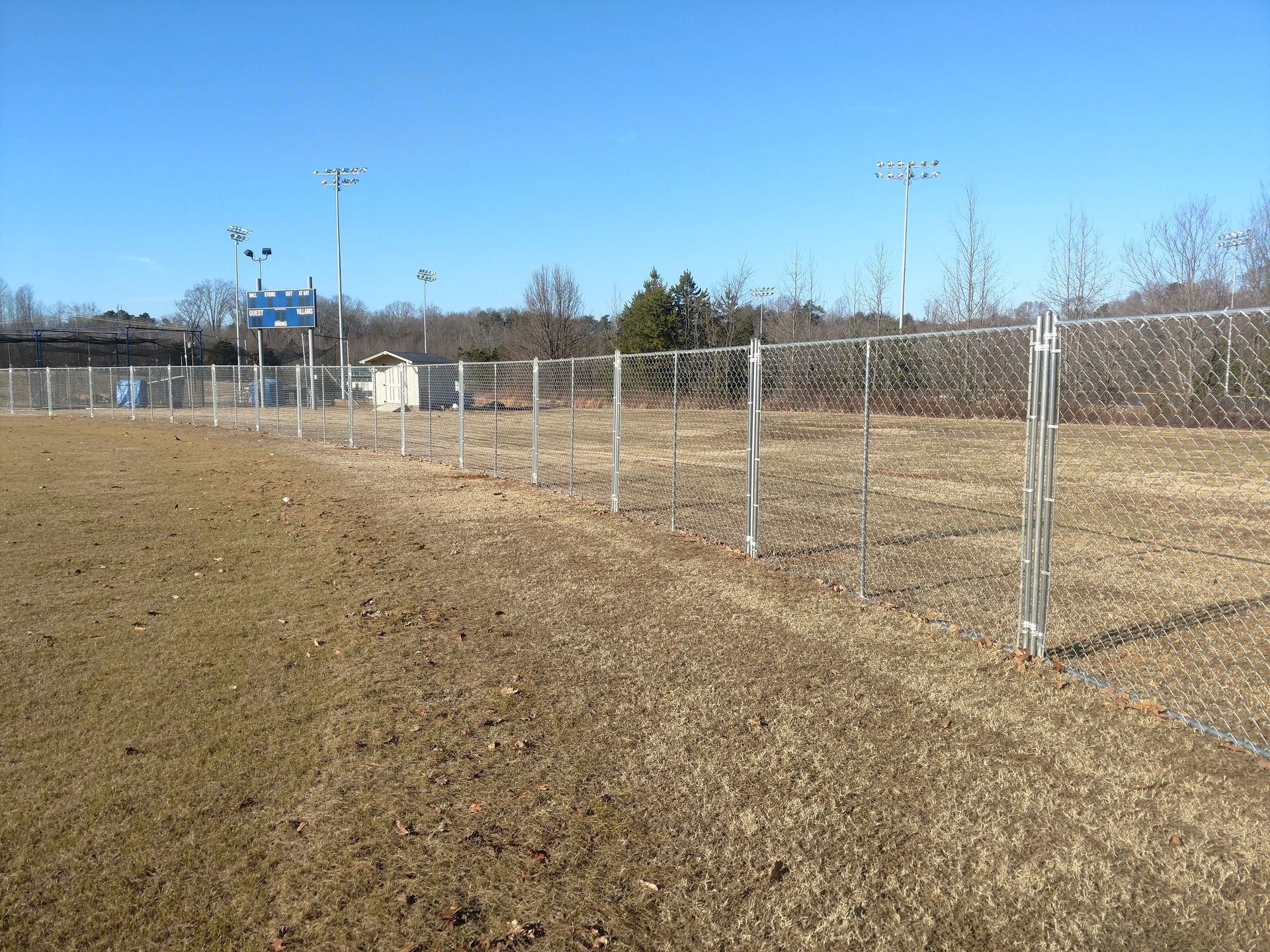 a chain link fence surrounds a field of dry grass