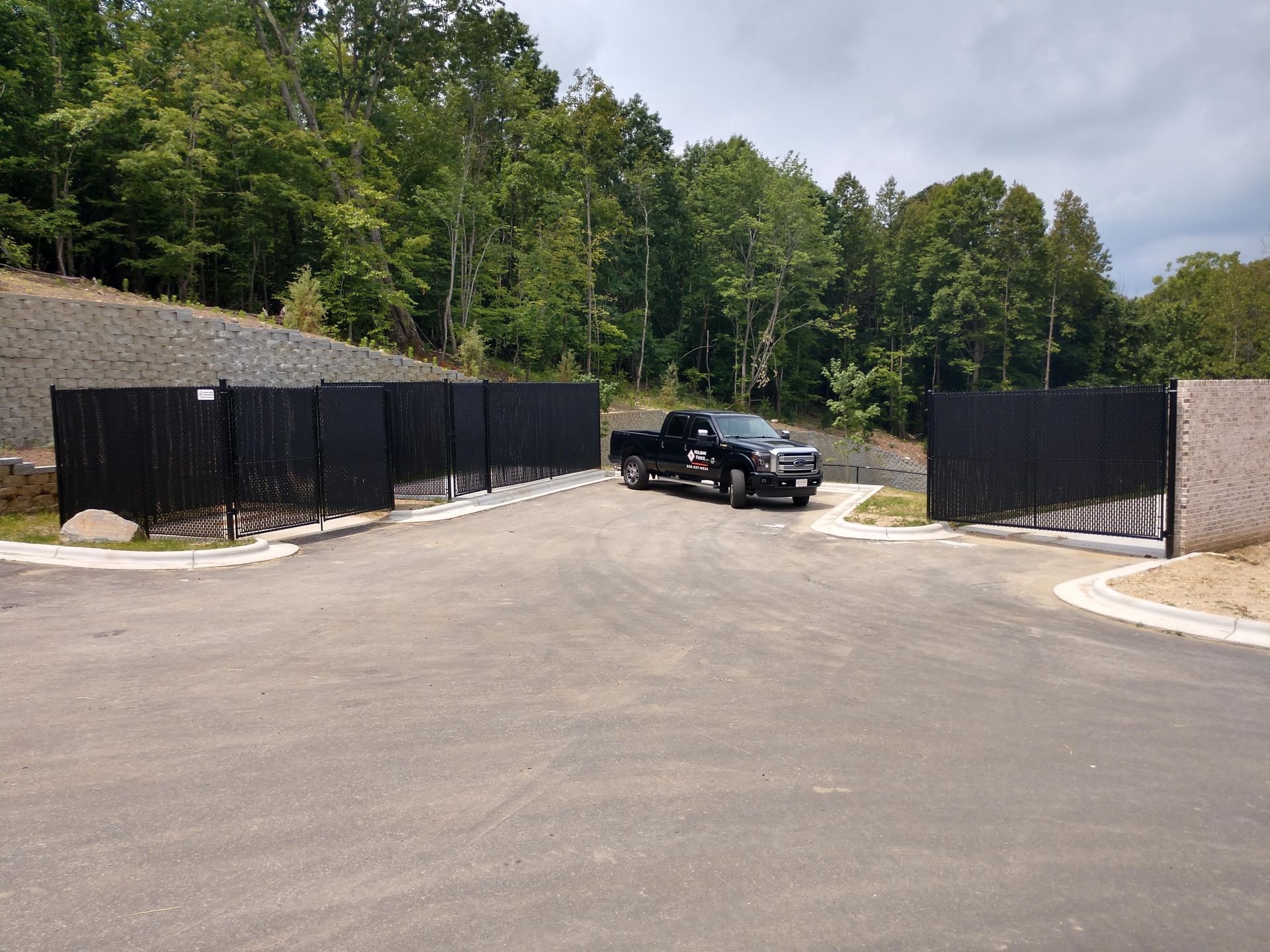 a black truck parked in the middle of a road next to a fence
