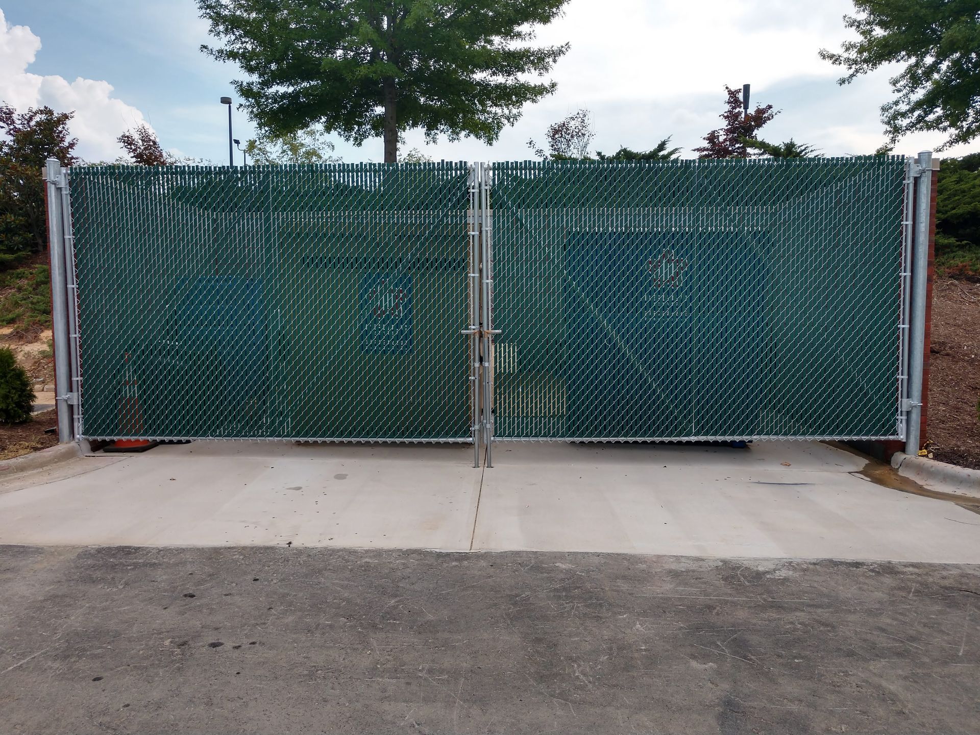 a green chain link fence surrounds a concrete driveway