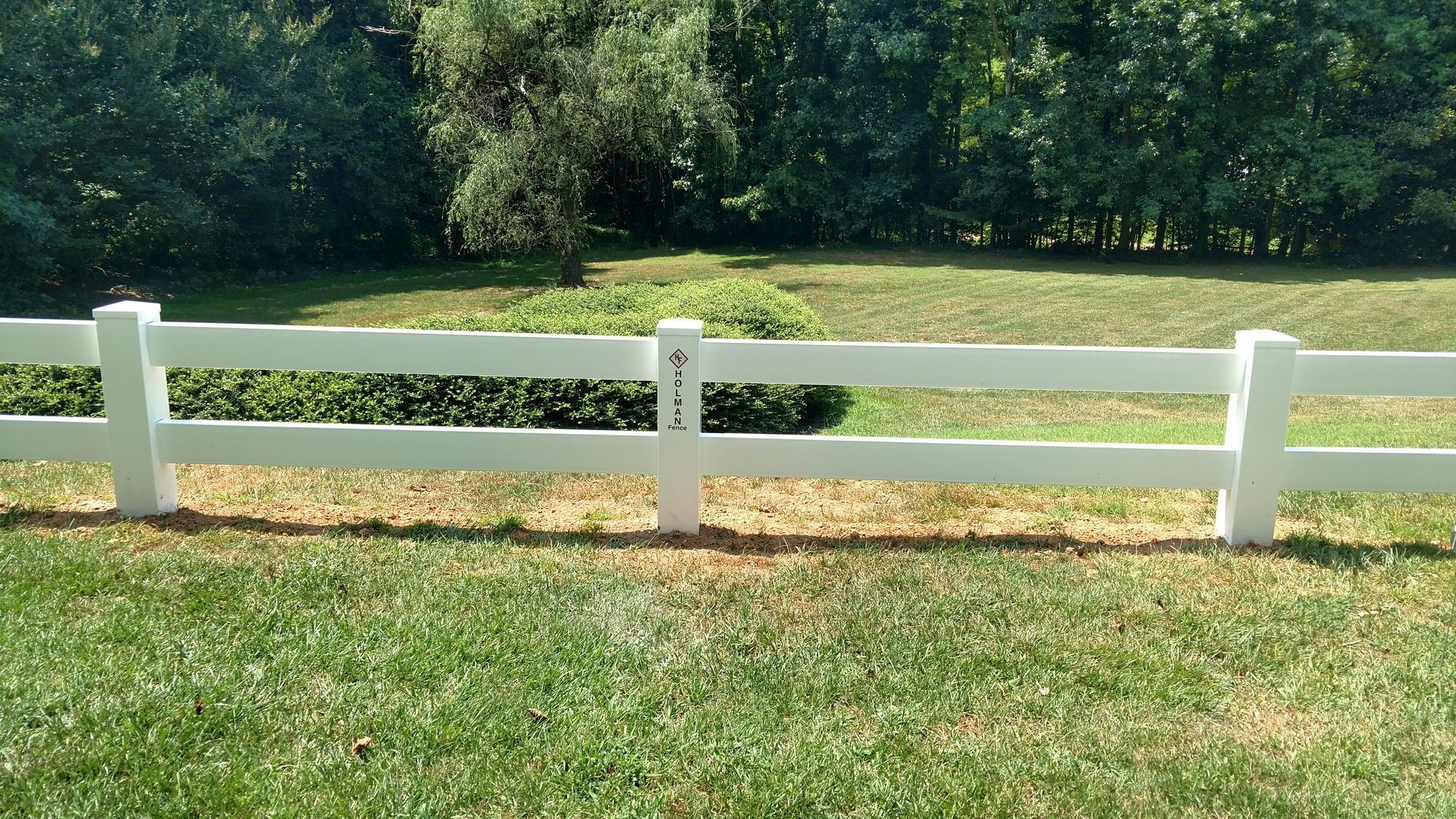 a white fence in the middle of a grassy field