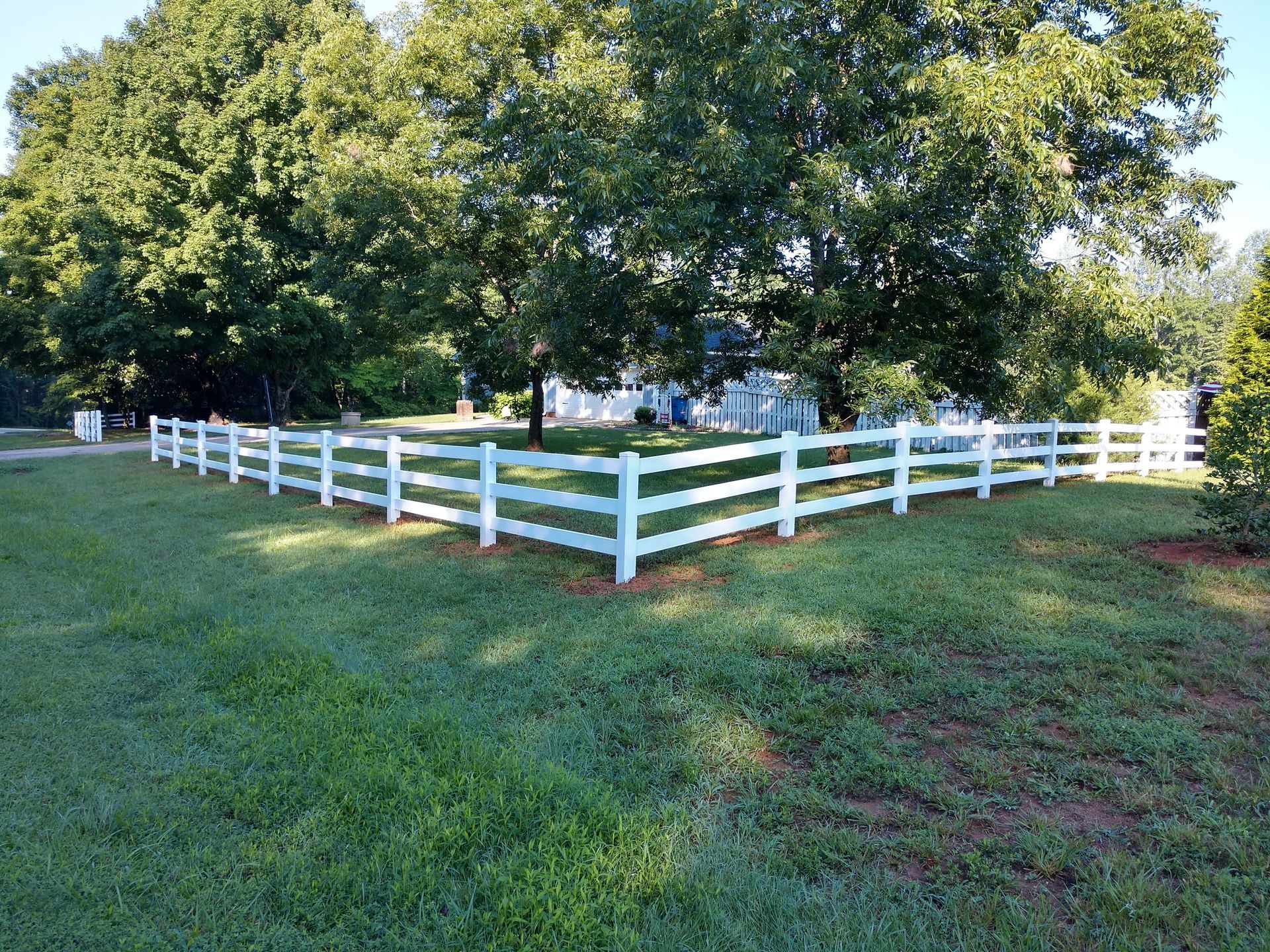a white fence in the middle of a lush green field