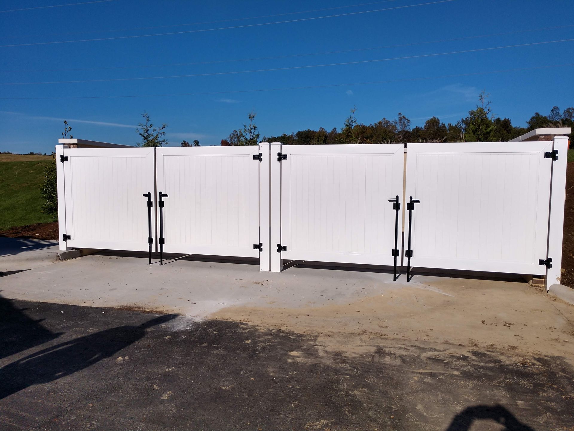 a white gate with black handles sitting on the side of a road