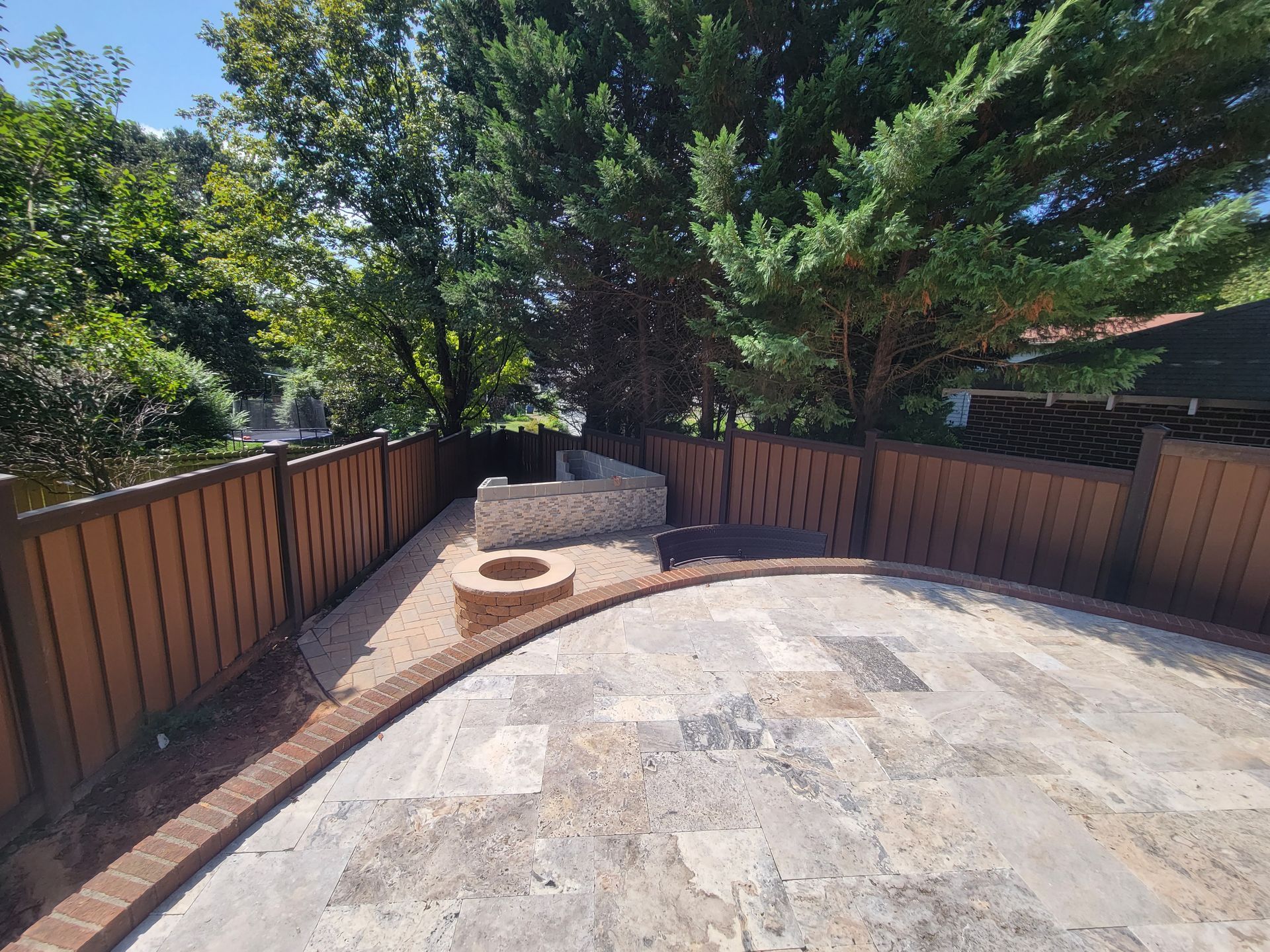 a wooden fence surrounds a patio with a fire pit