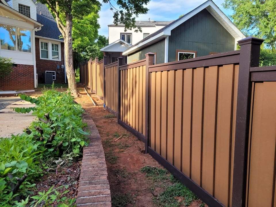 a wooden fence surrounds a brick walkway leading to a house