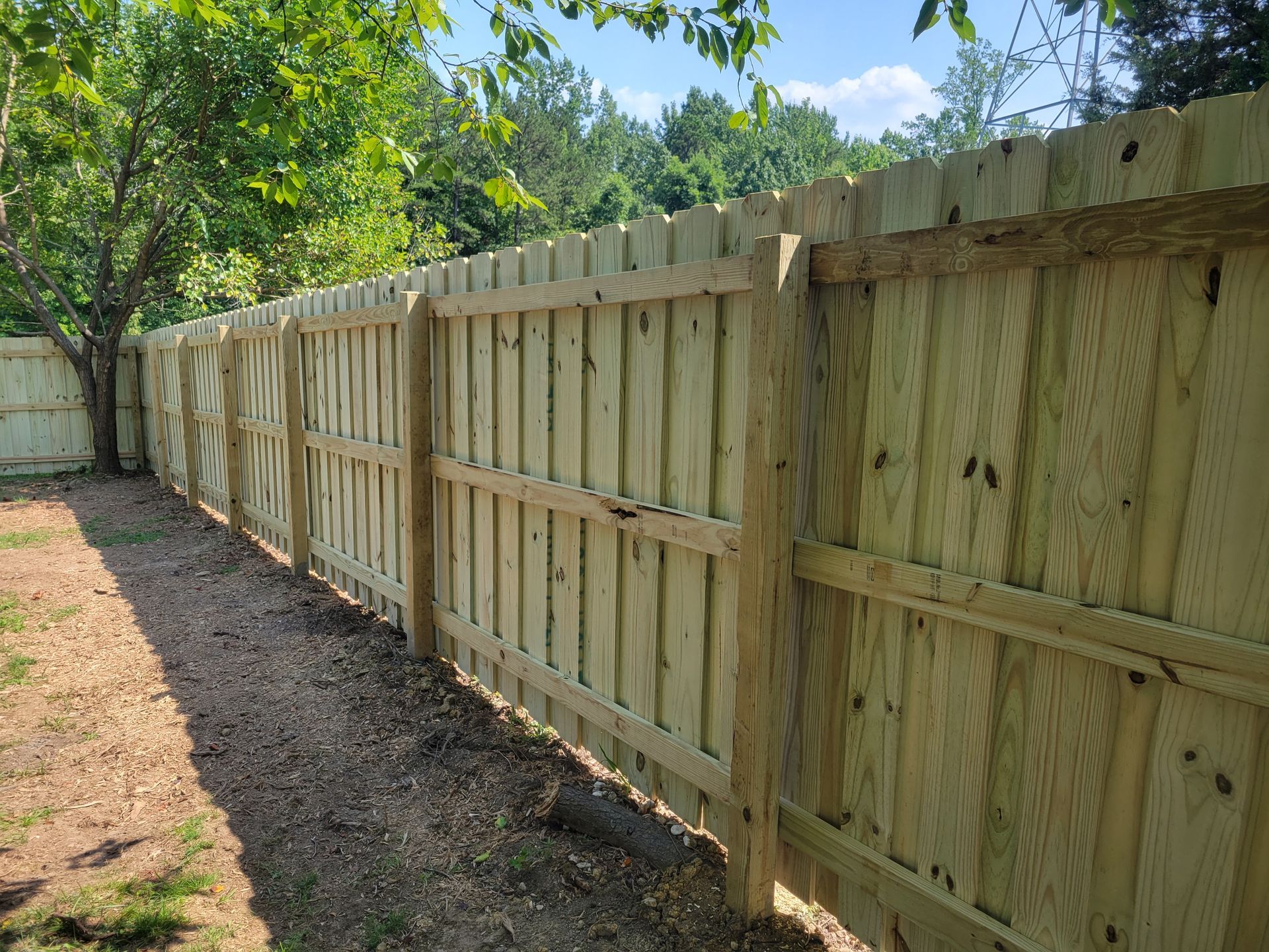 a wooden fence surrounded by trees in a backyard