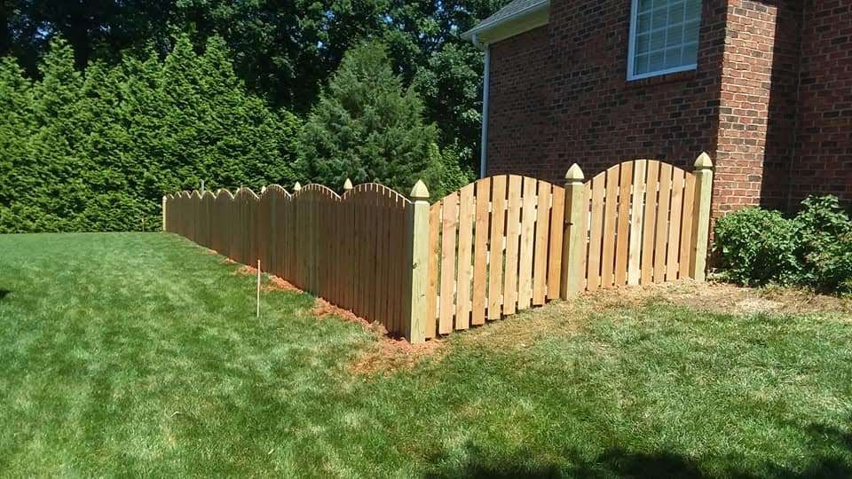 a wooden picket fence in front of a brick house