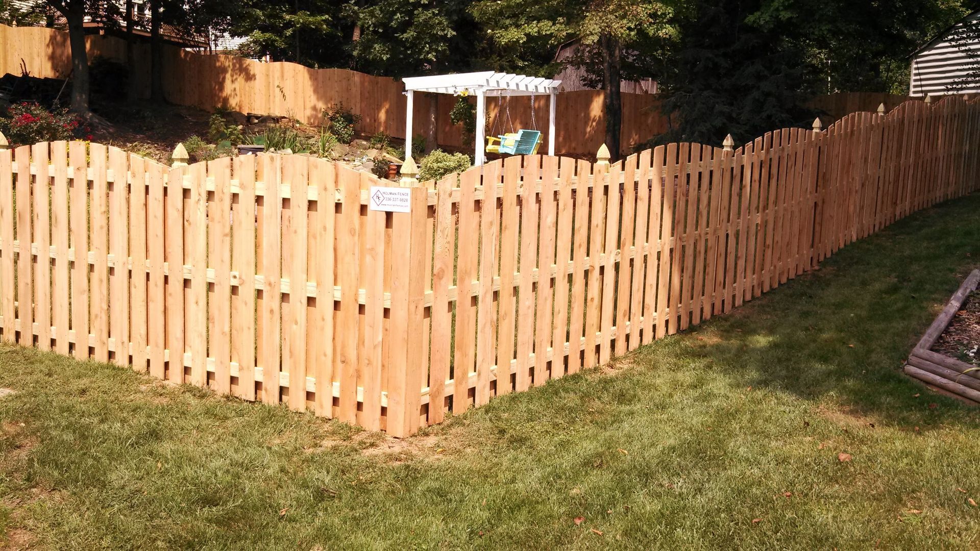 a wooden picket fence in the middle of a lush green yard