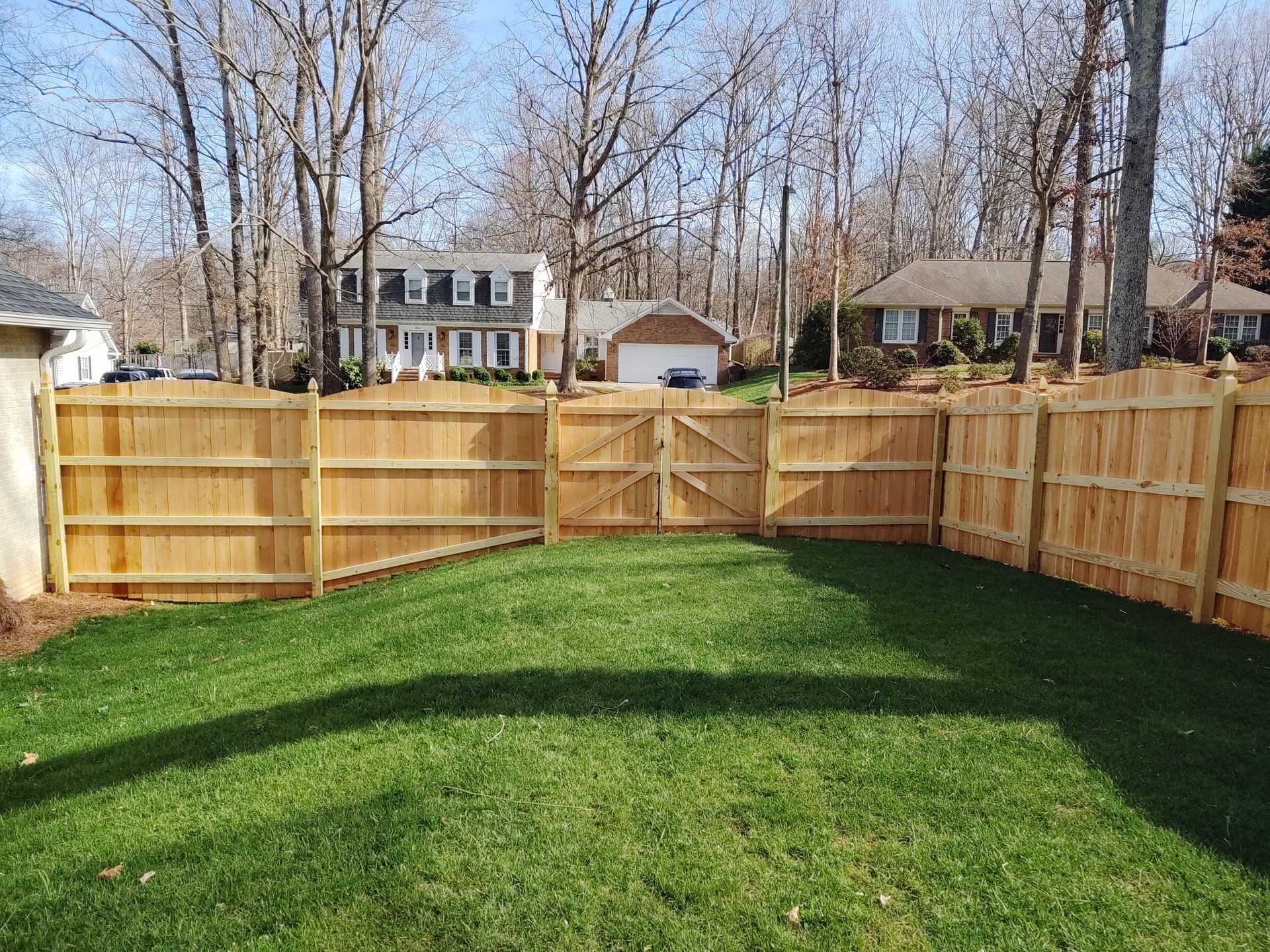 a wooden fence surrounds a lush green lawn in a backyard