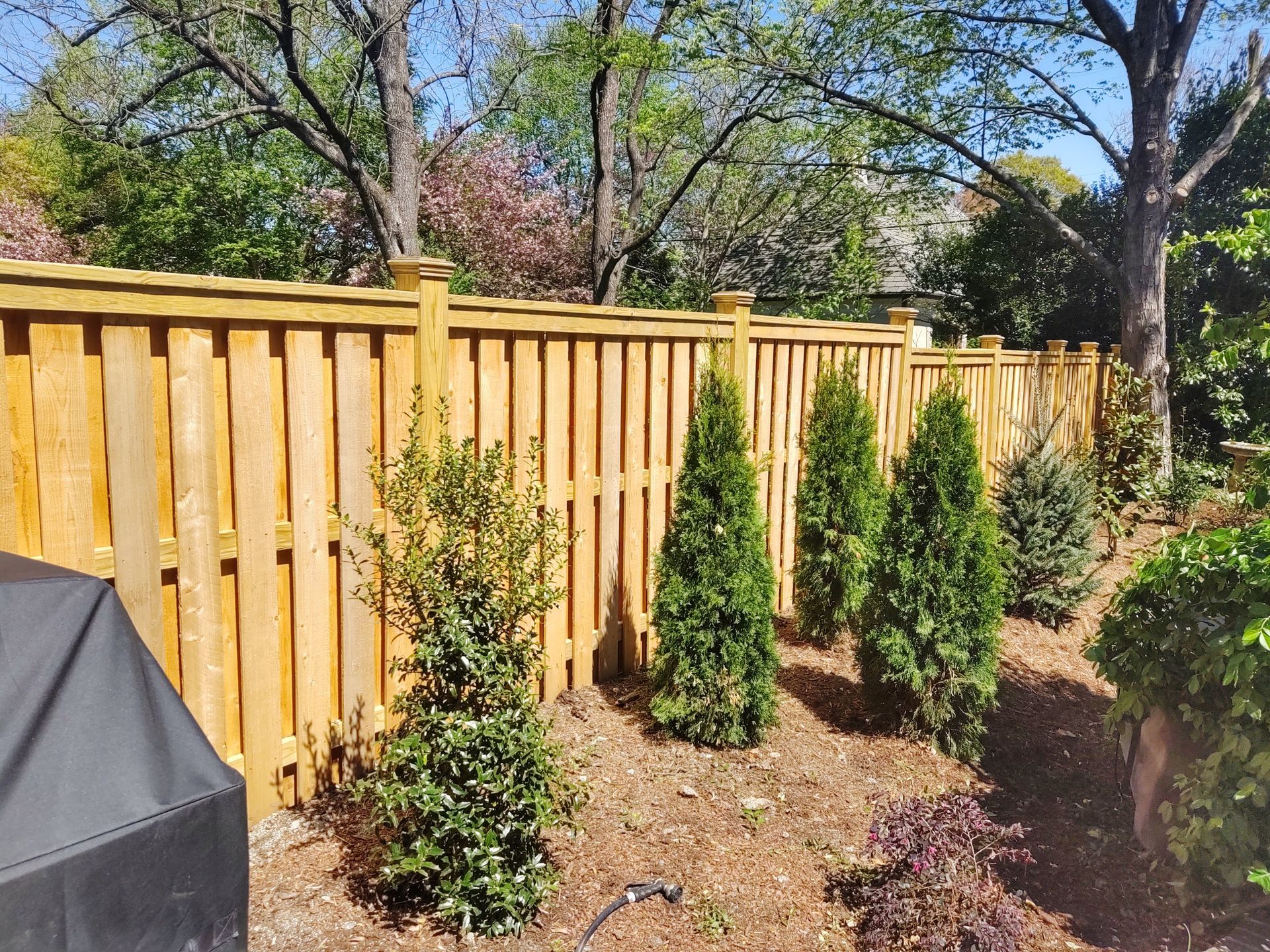 a wooden fence surrounded by trees and bushes in a backyard