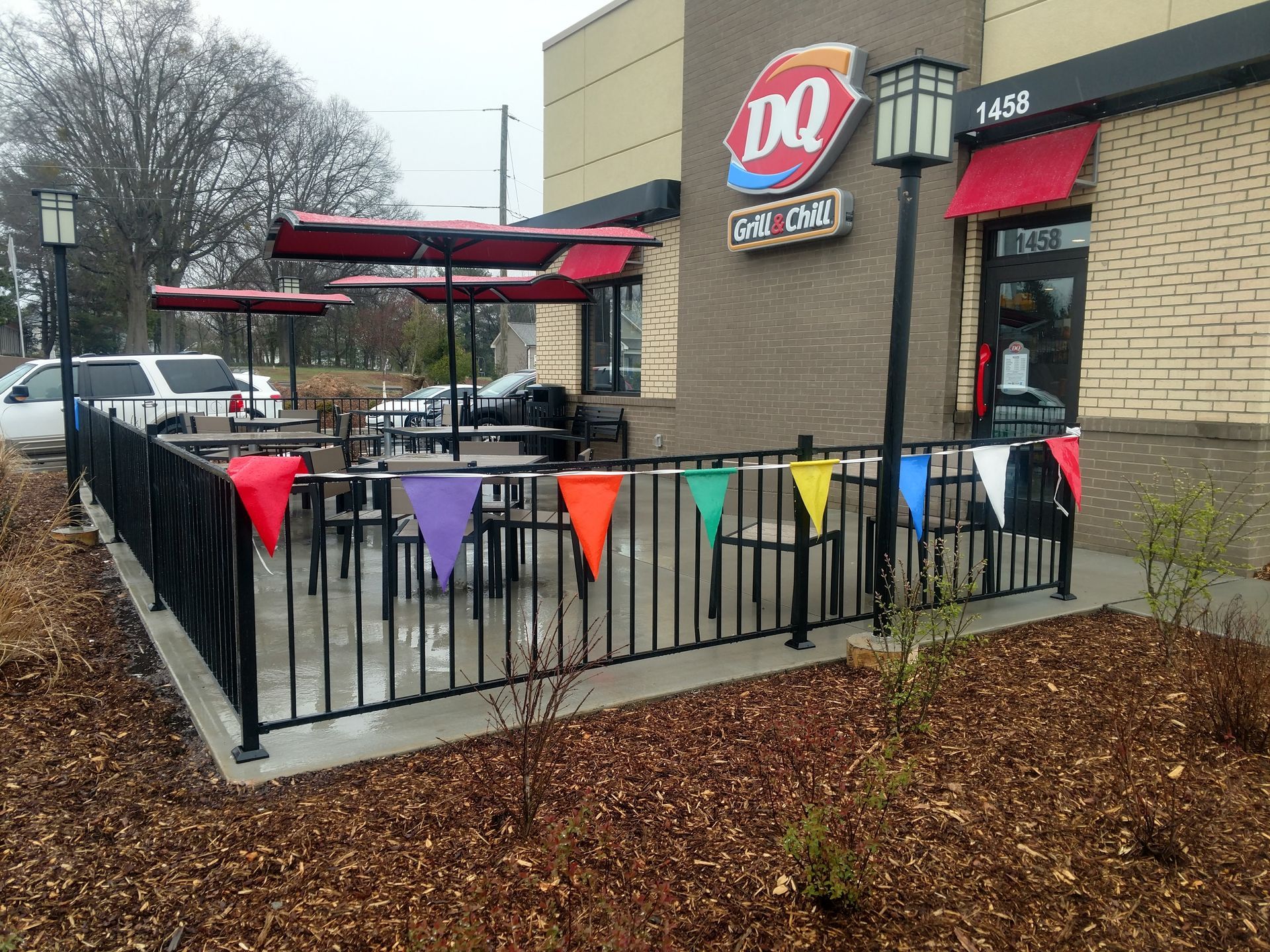 The outside of a dairy queen restaurant with tables and umbrellas