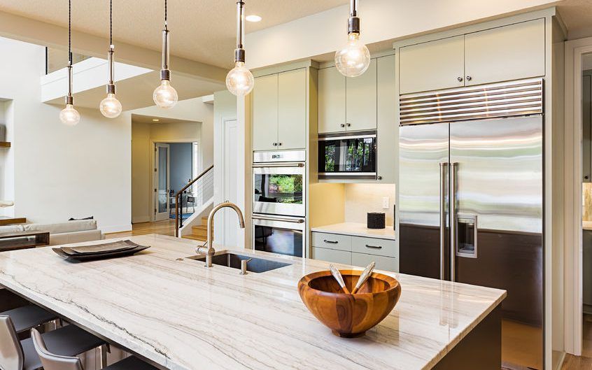 A kitchen with stainless steel appliances and a large island with a bowl on it.