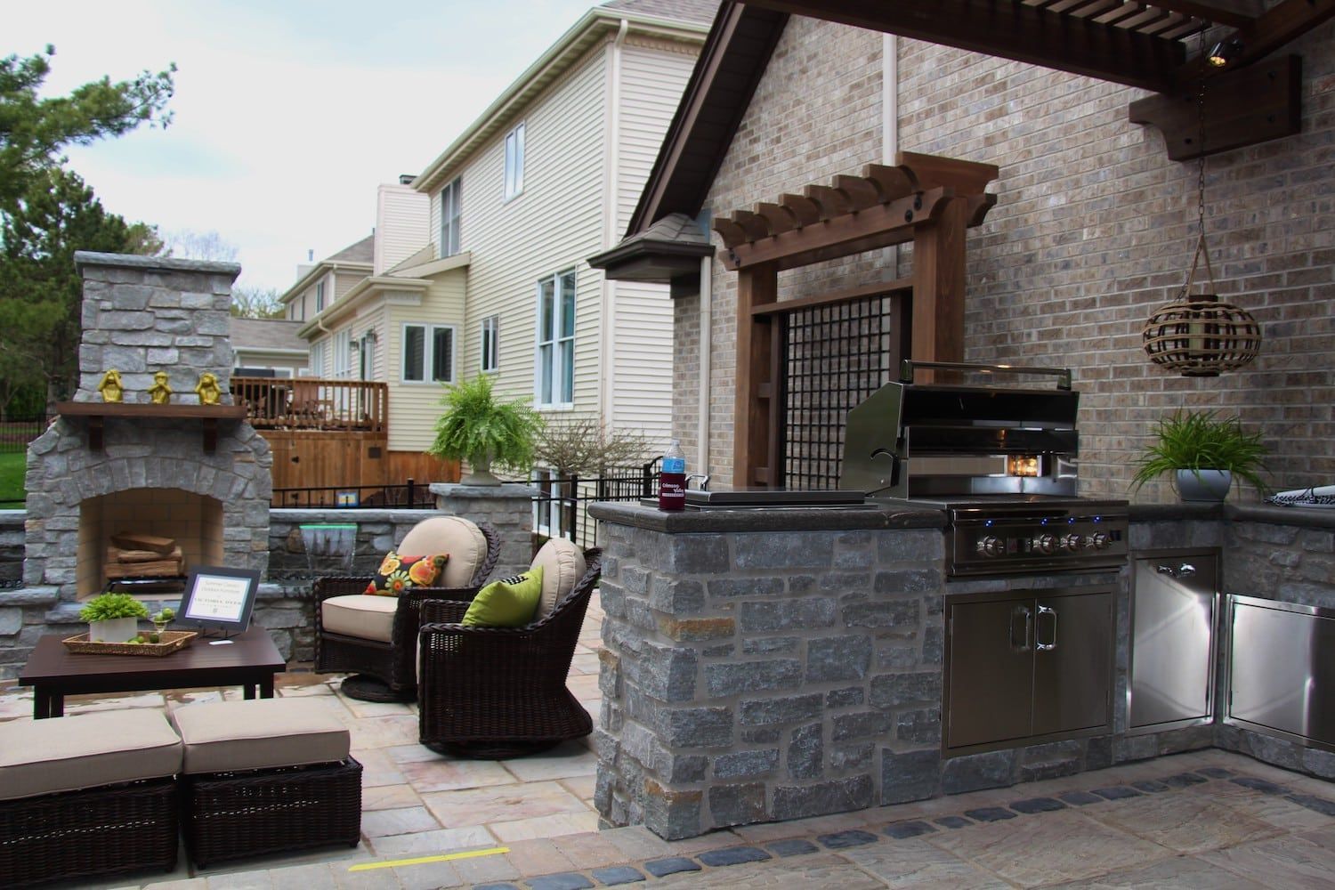 Outdoor kitchen with stone fireplace, grill, and seating area.
