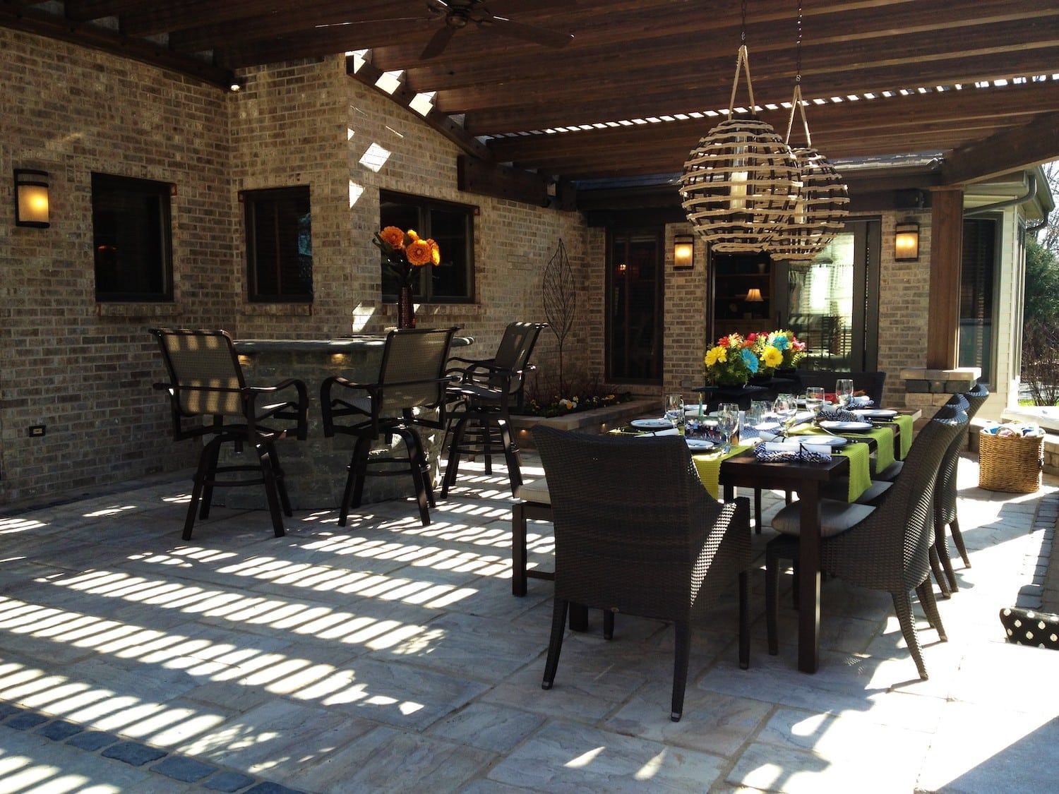 Outdoor dining area with brick walls, a wooden pergola, and a table set for a meal.