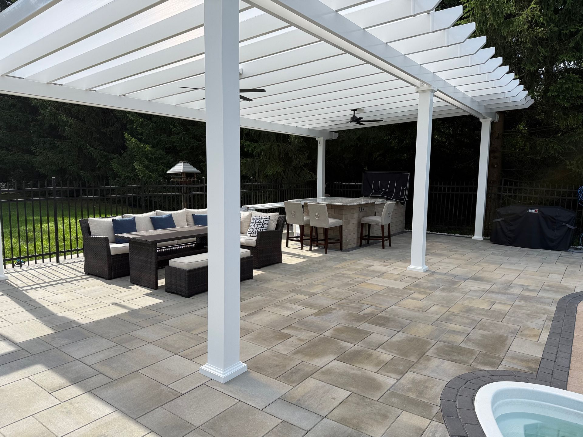 Outdoor patio with white pergola, seating area, and a built-in bar.