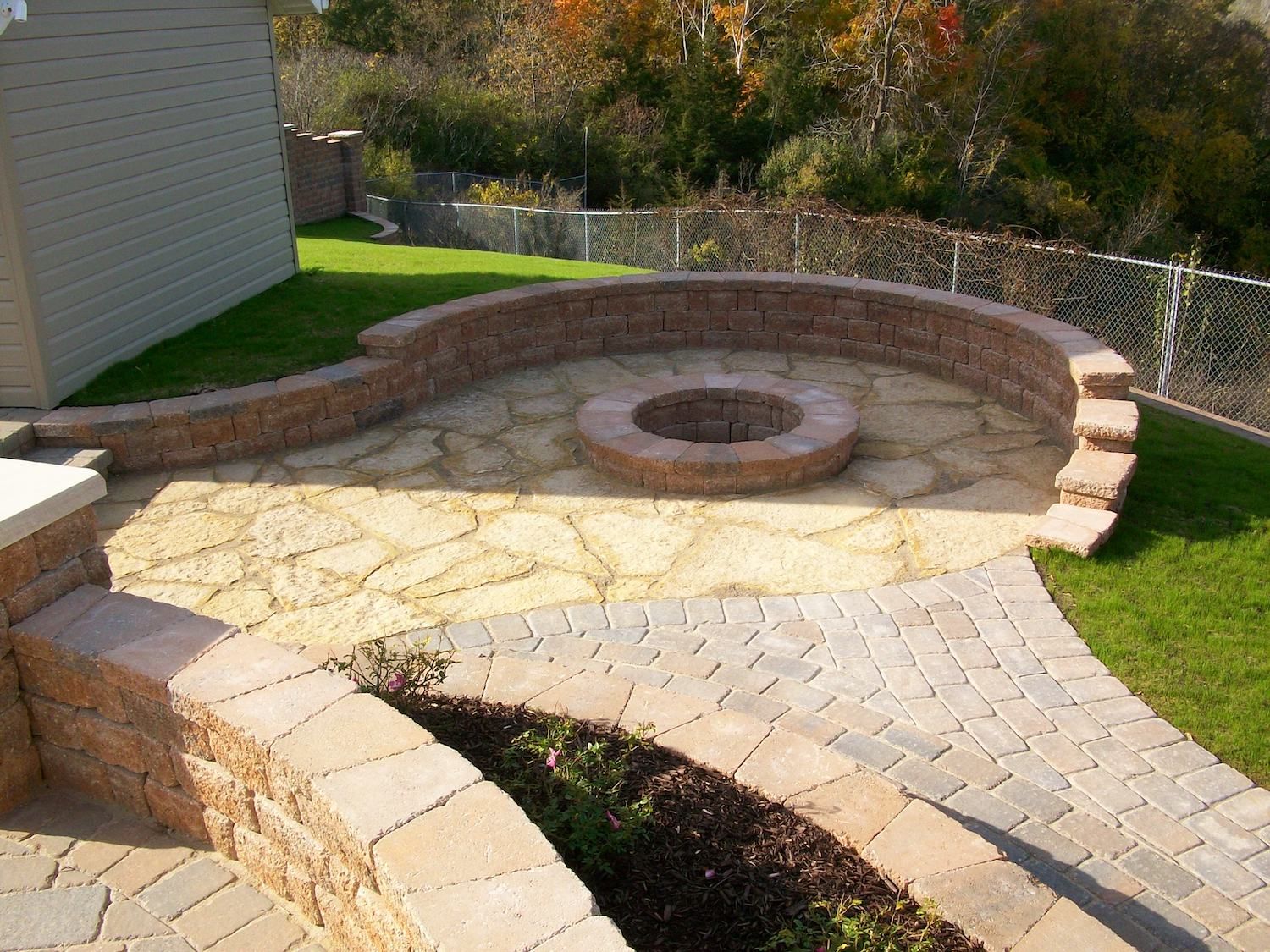 Brick patio with curved retaining walls, a fire pit, and landscaping.