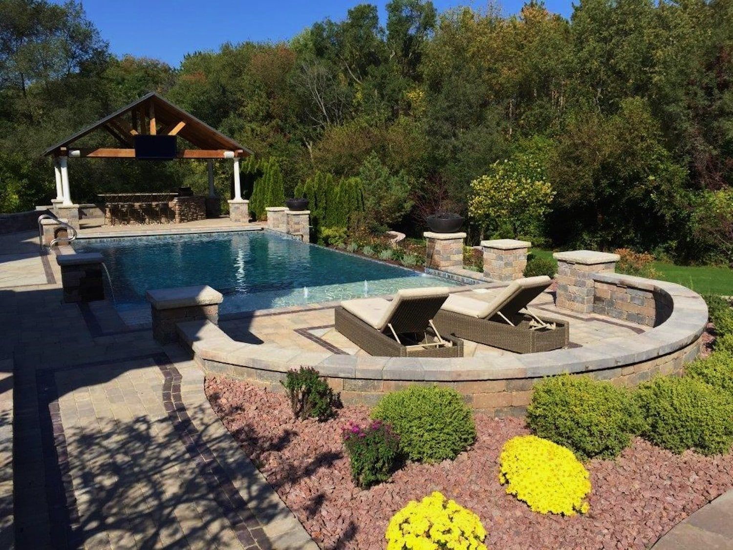 Pool area with lounge chairs, a gazebo, and colorful landscaping.
