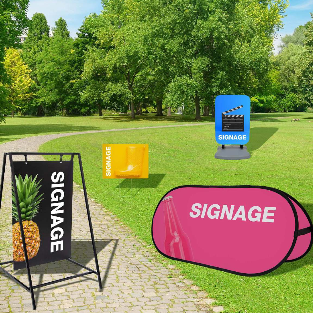 A sign that says `` signage '' is sitting on a sidewalk in a park.