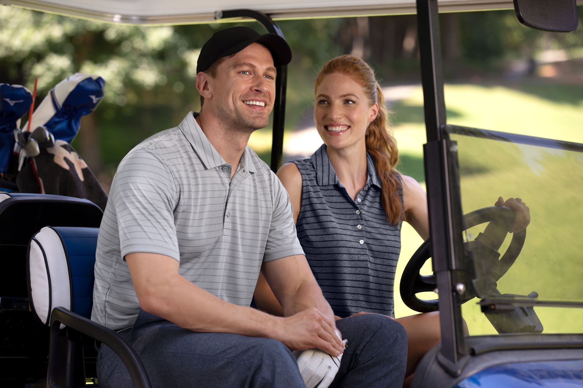 A man and a woman are sitting in a golf cart.