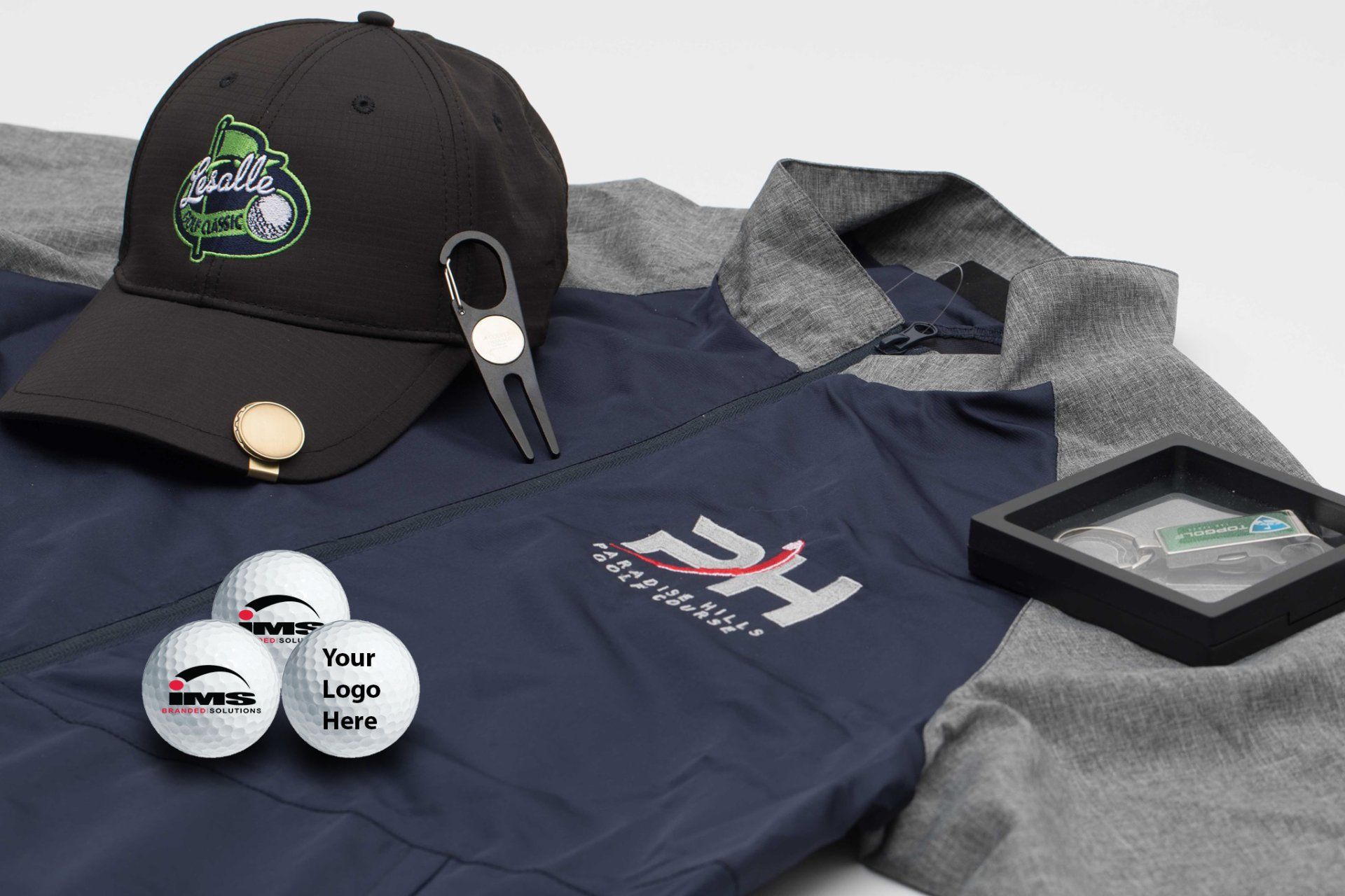 A hat , golf balls , a pitchfork , and a shirt are on a table.