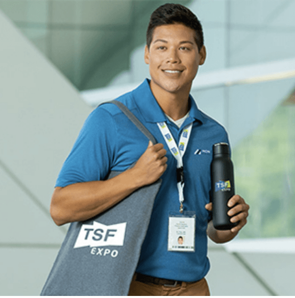 A man holding a water bottle and a bag that says tsf expo