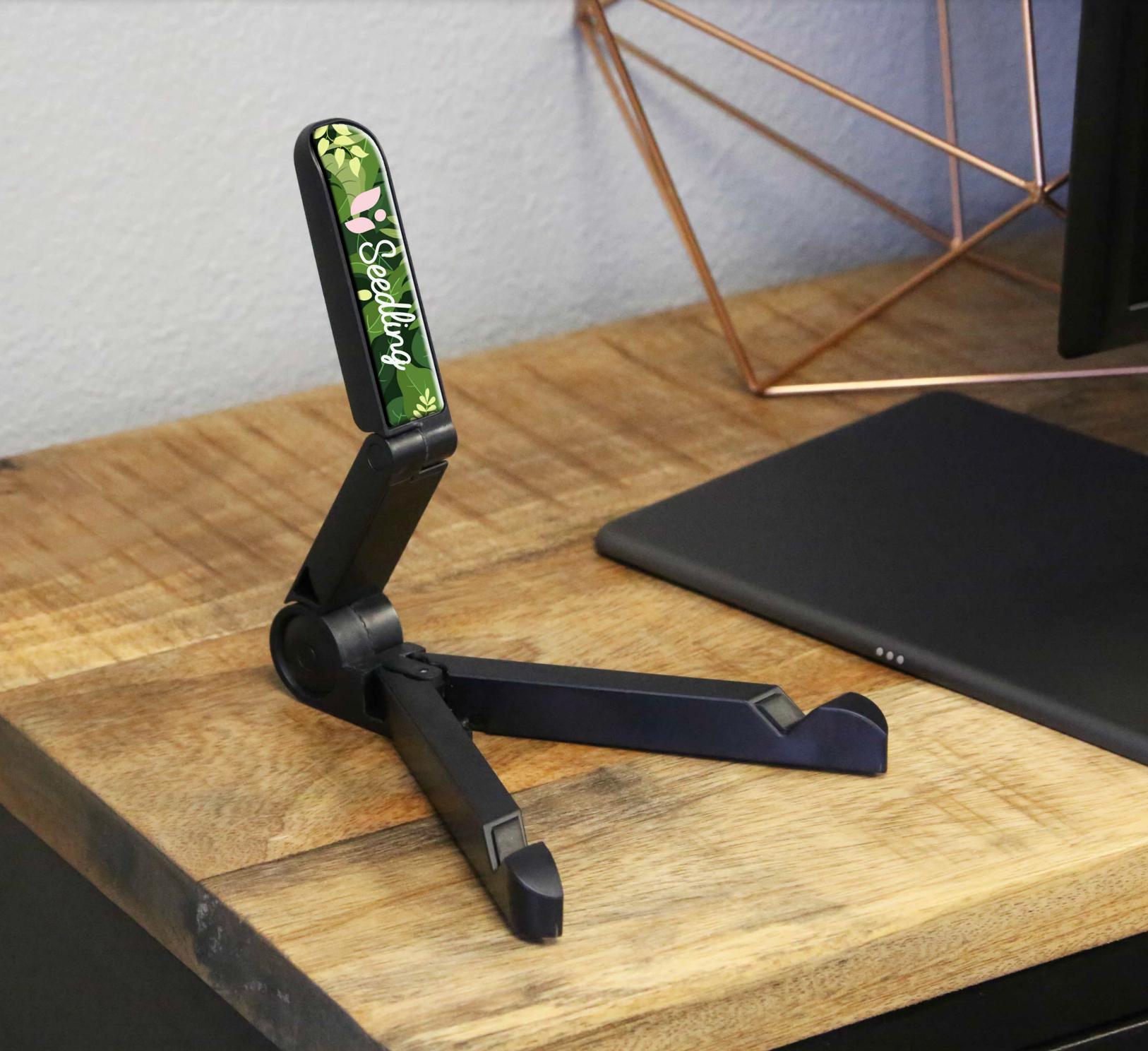 A phone holder with a camouflage design is sitting on a wooden table