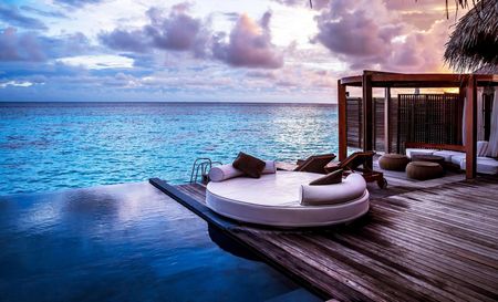 A round bed is sitting on top of a wooden deck overlooking the ocean.