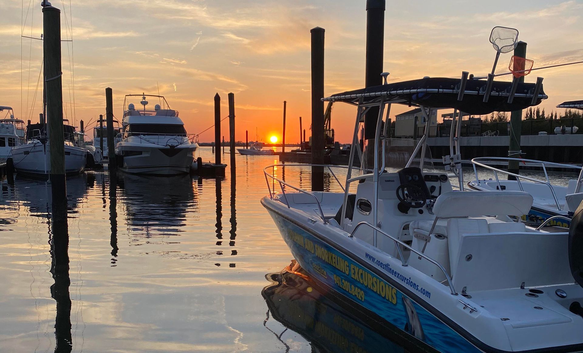 A boat is docked in a marina at sunset.