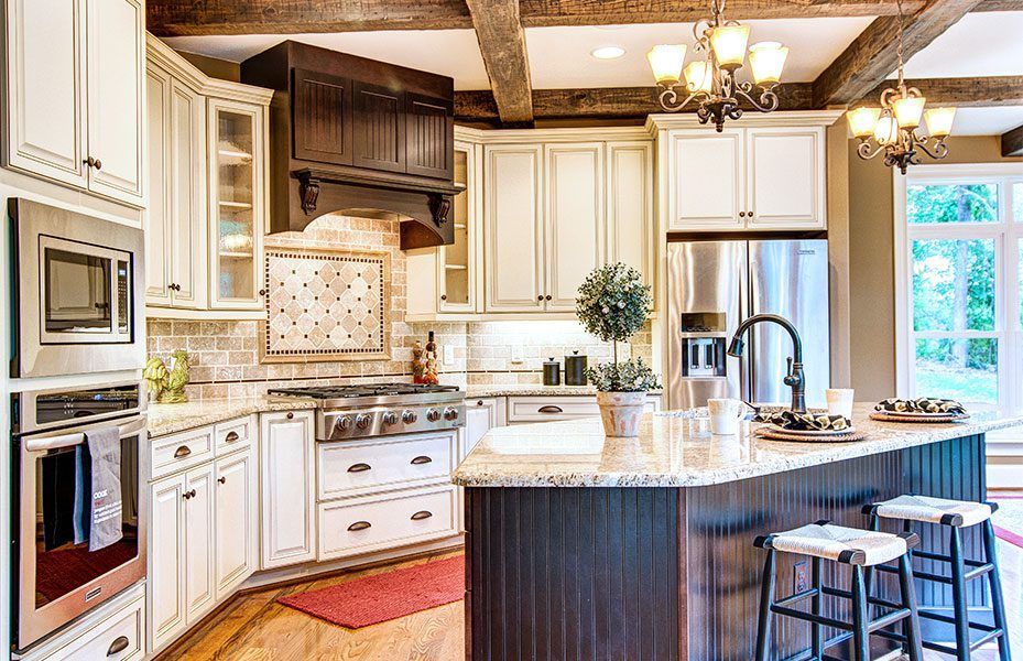 A kitchen with white cabinets , stainless steel appliances , granite counter tops and a large island.