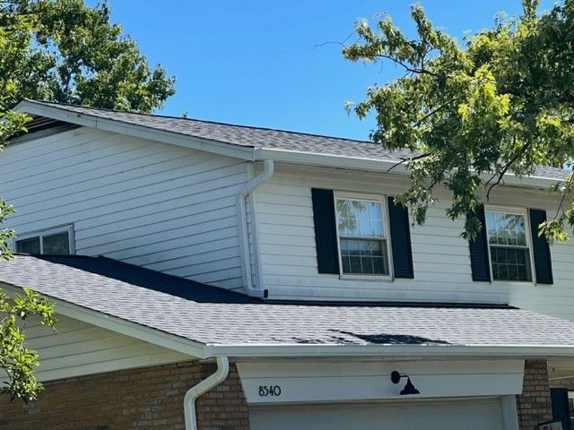 A white house with a black roof and black shutters.